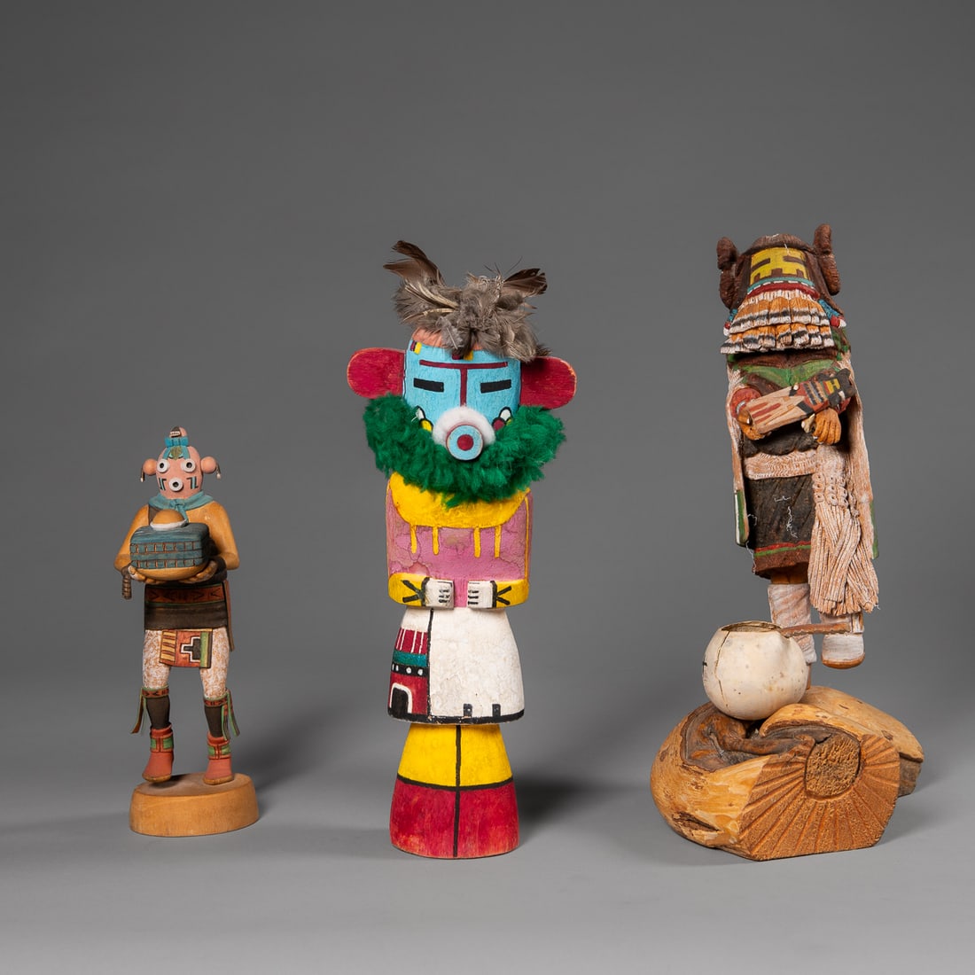 Three contemporary Hopi kachinas: An unsigned kachina with red and yellow cone legs, a Mudhead by Ken Shupla, and a Yellow Corn Madian "mana," kachina. Ht. 12, 9 1/2 and 14 1/2 in.