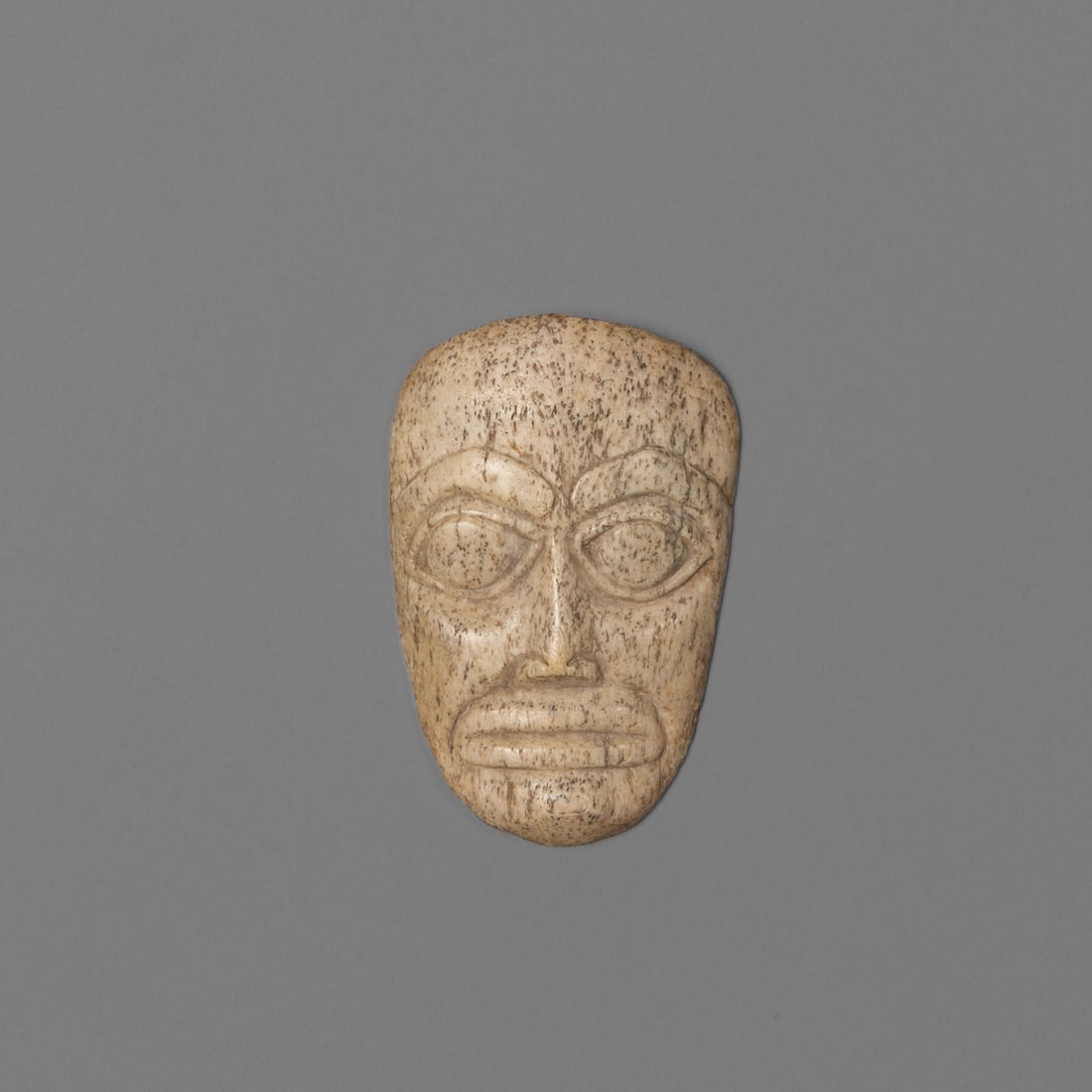A Northwest Coast carved face: Fourth quarter 19th century, finely carved with typical Northwest Coast clan form line features, with old paper label, "5676." Ht. 3 1/2, wd. 2 1/4 in. Provenance: Private collection, Belle Fourche, S