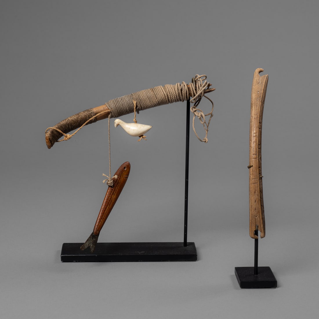 A Bering Sea Eskimo fish decoy and box handle: 19th century, the fish decoy handle wrapped in period cord, slightly curved at tail end, with notched tip, the white carved bird with detailed eyes, pointed beak, and pinched tail feather end, the