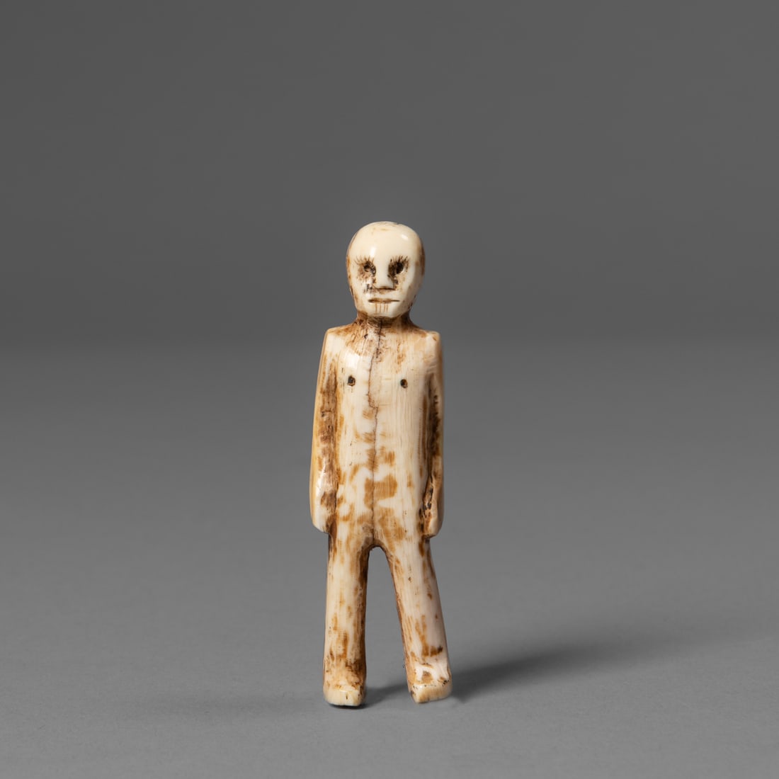 An Eskimo carved figure: 19th century, the standing male figure in bone with arms to the sides, the head with deep-set eyes. Ht. 2 3/4 in. Provenance: Private collection, Belle Fourche, South Dakota.
