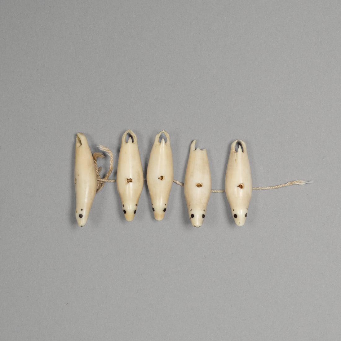 Five Bering Sea Eskimo Toggles: Alaska, late 19th/early 20th century. carved bone with rich golden-brown patina. Minor loss to one tail. Toggles or possibly from a seal hunting necklace. Provenance: Paul and Mary Thiry Collection,