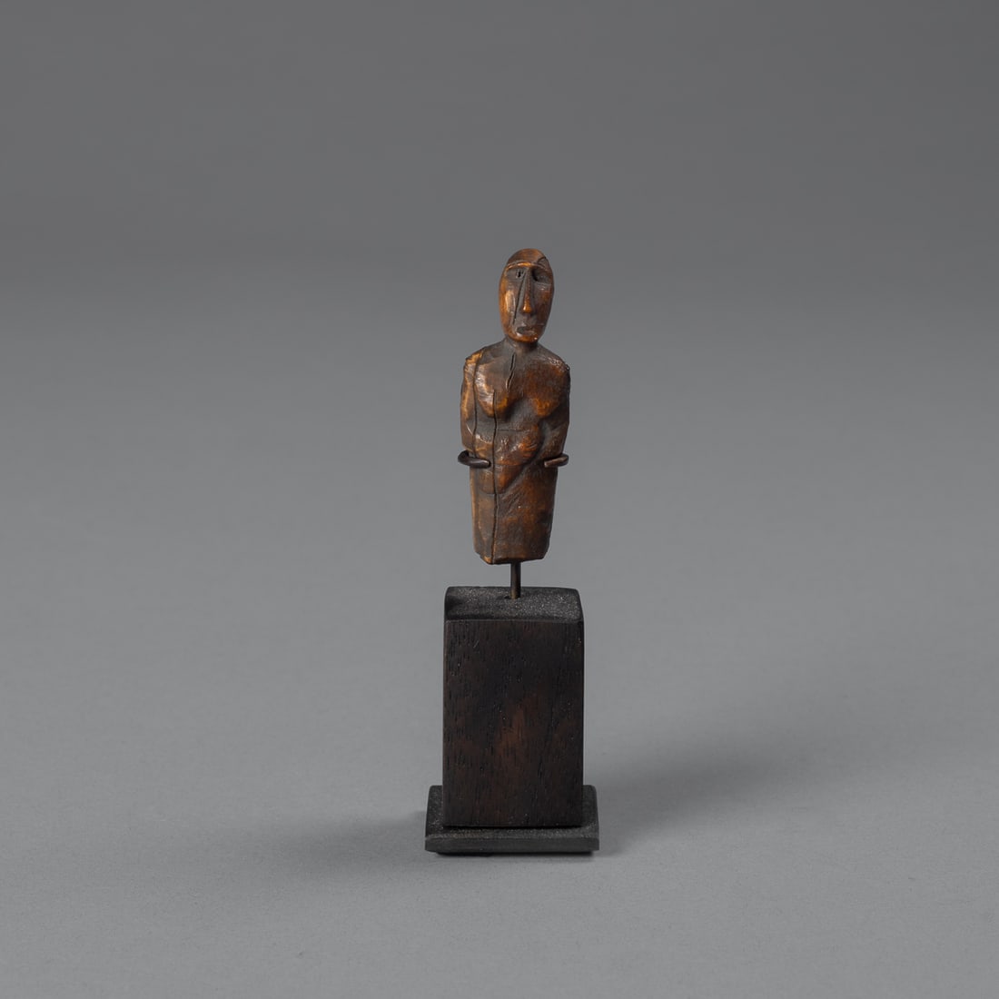 An Eskimo figure: St Lawrence Island, Alaska, Punuk or Thule period, the female torse with hands to the waist, right hand looks to be holding an object, the head with elongated nose and slit eyes and mount. Mounted on