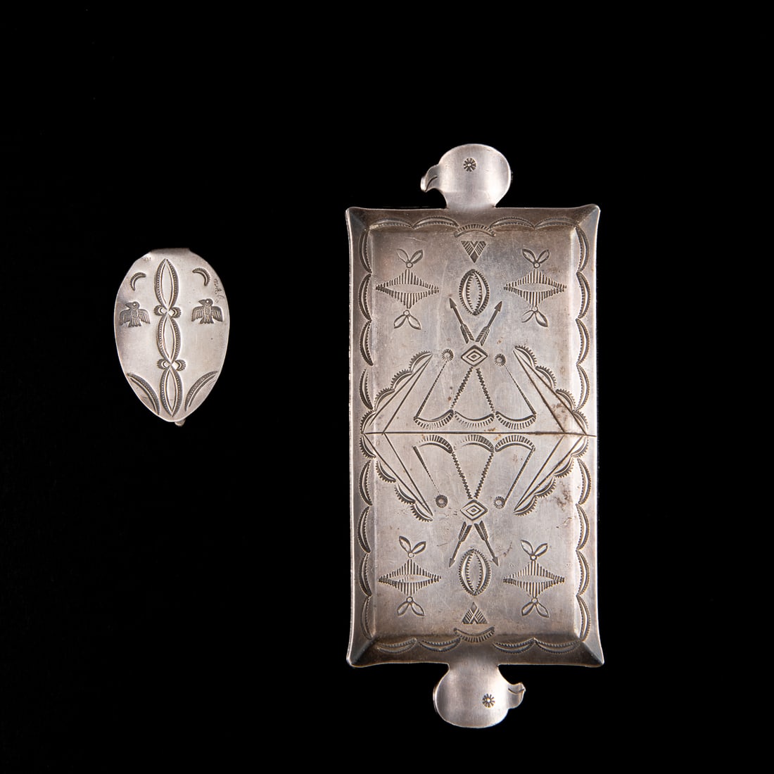 A Navajo silver ash tray and money clip: The rectangular ashtray with complex stamp work, including arrows, each end with bird-head cigarette rests, with a silver money clip with stamp work including thunderbirds. Lg. 5 ¾, wd. 2 1/2,
