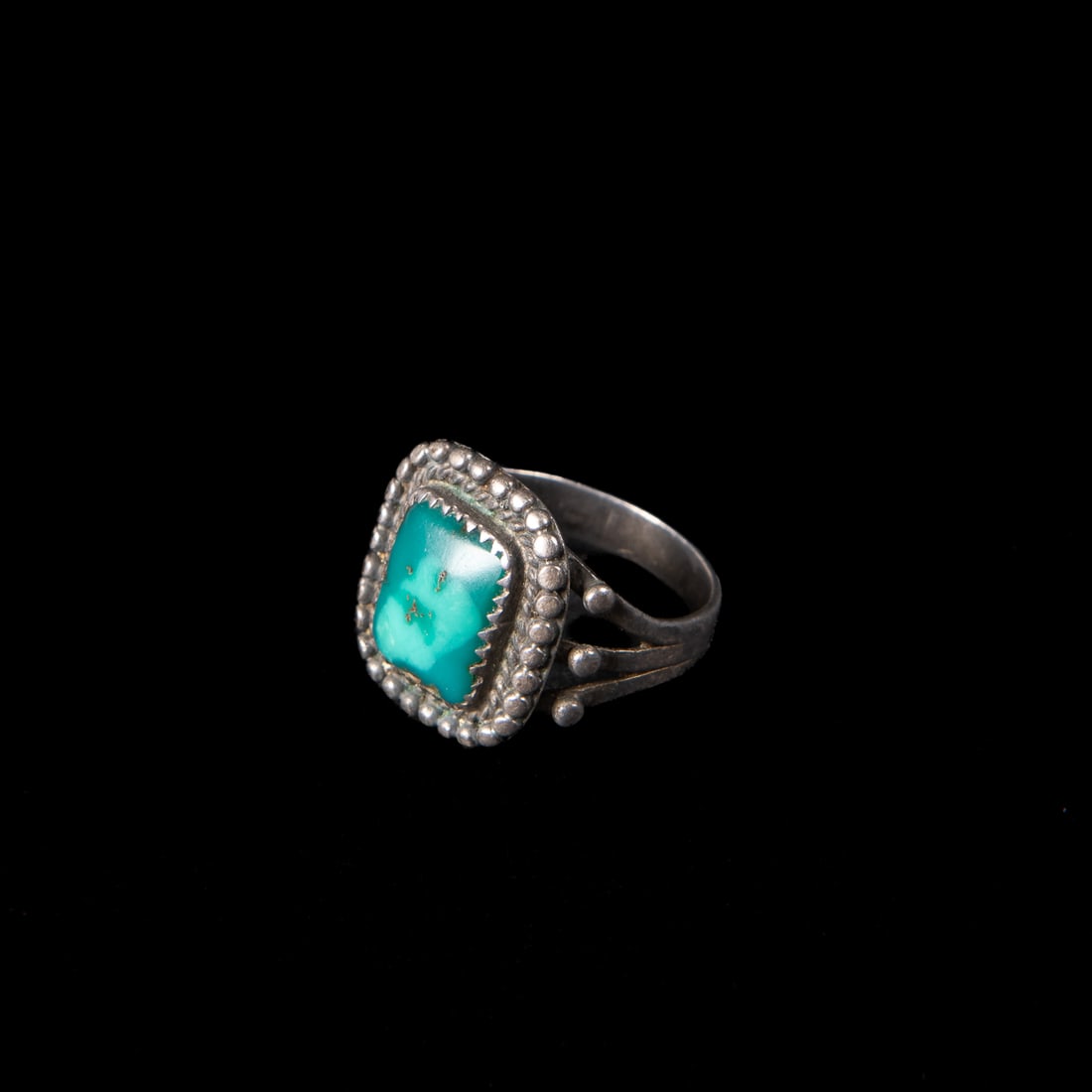 A Navajo silver and turquoise ring: Early 20th century, the silver ring with ball and ropework surrounding a rectangular turquoise setting. Gross weight 11 grams. Ring size 8 ¾.