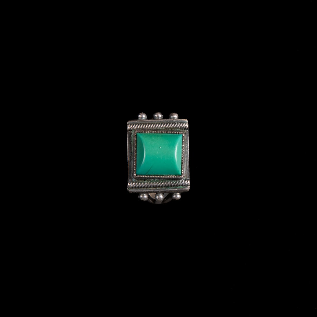 A Navajo silver and turquoise ring: Early 20th century, the silver ring with six silver balls and green turquoise setting. Gross weight 9 grams. Ring size 10.