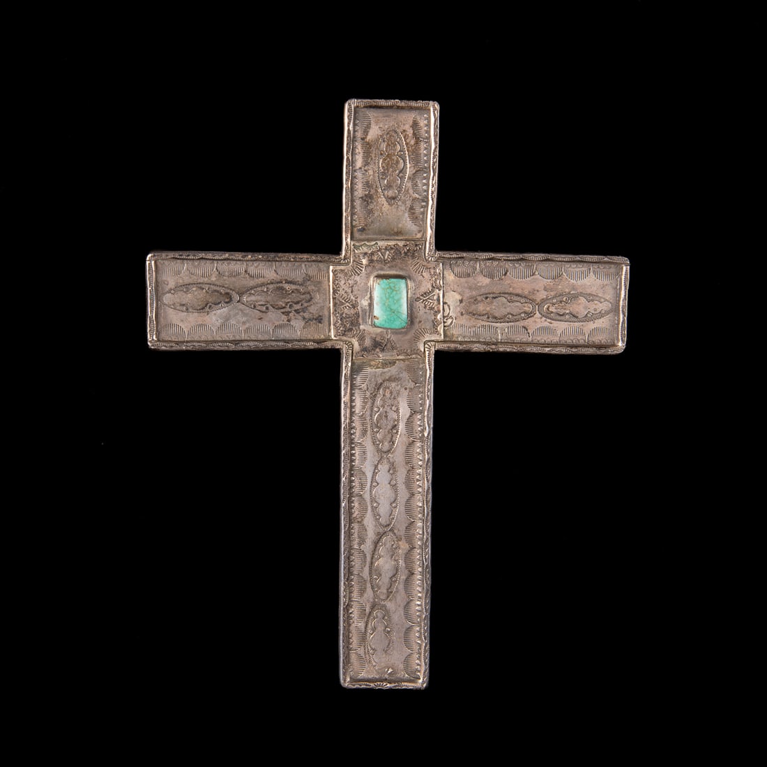 A Navajo silver and turquoise cross: The large heavy silver cross, decorated with stamped designs, the center with a rounded turquoise setting. Lg. 7 ½, wd. 5 7/8 in. Gross weight 283 grams.