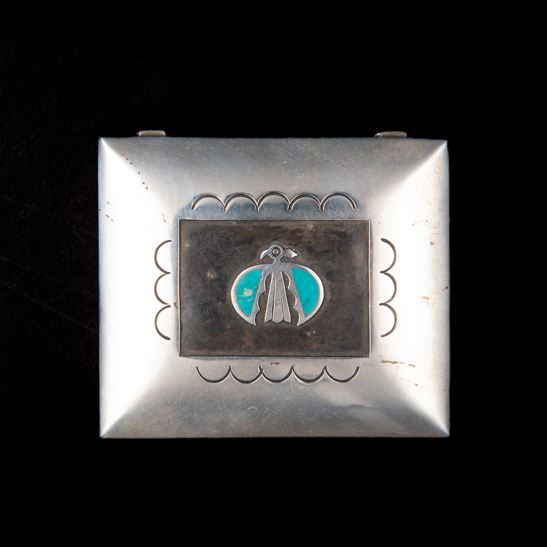 A Hopi inlaid silver box: Mid 20th century, the square silver box with lid decorated with chisel work and overlay bird motif with turquoise inlay wings, unmarked. Ht. 1, wd. 3 1/4, lg. 2 7/8 in. Gross weight 165 grams.