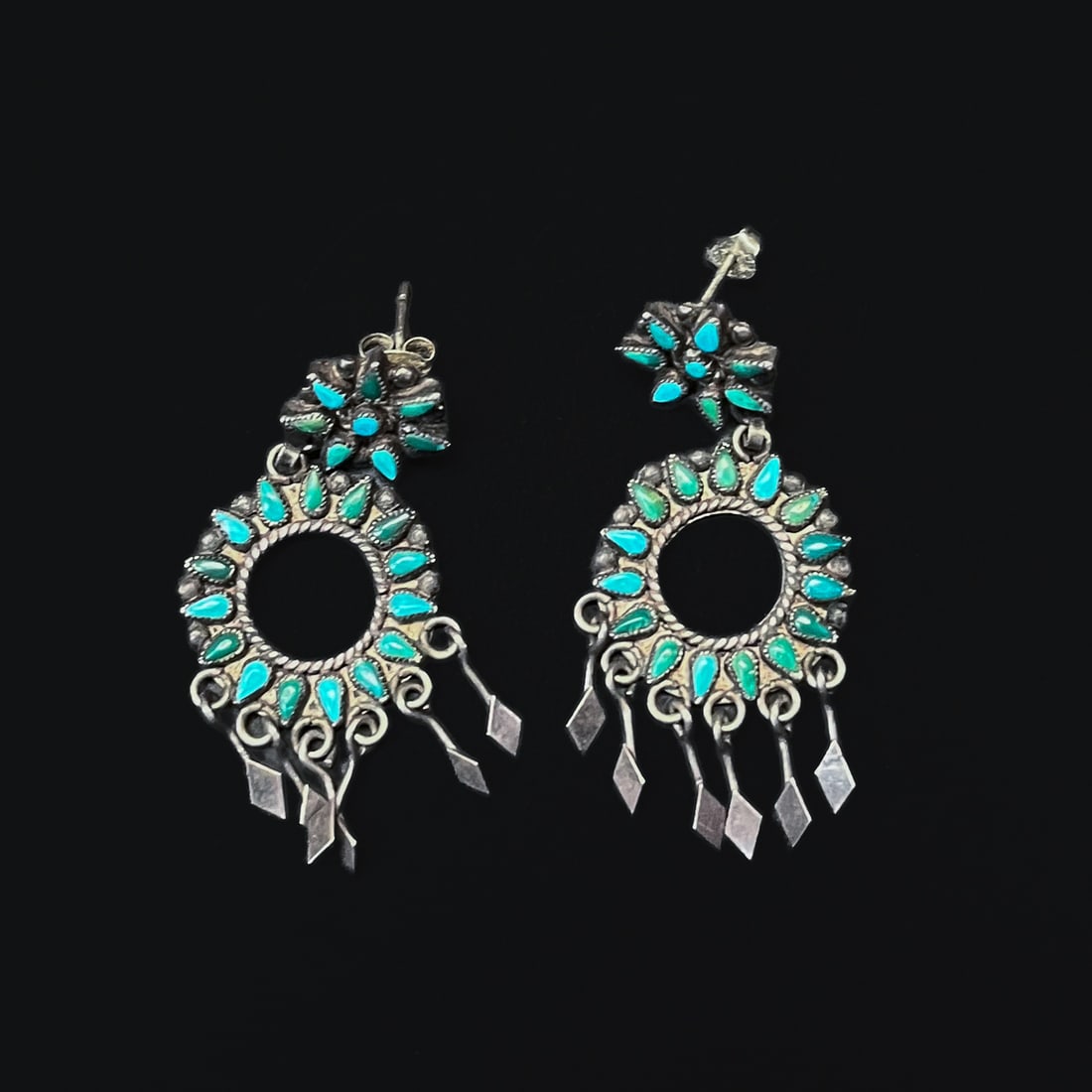 A pair of Zuni petit-point earrings: The pair of earrings with circular stud with central small turquoise setting, surrounded by small alternating blue and green petit-point turquoise, attached to a circular dangle of 15 petit-point