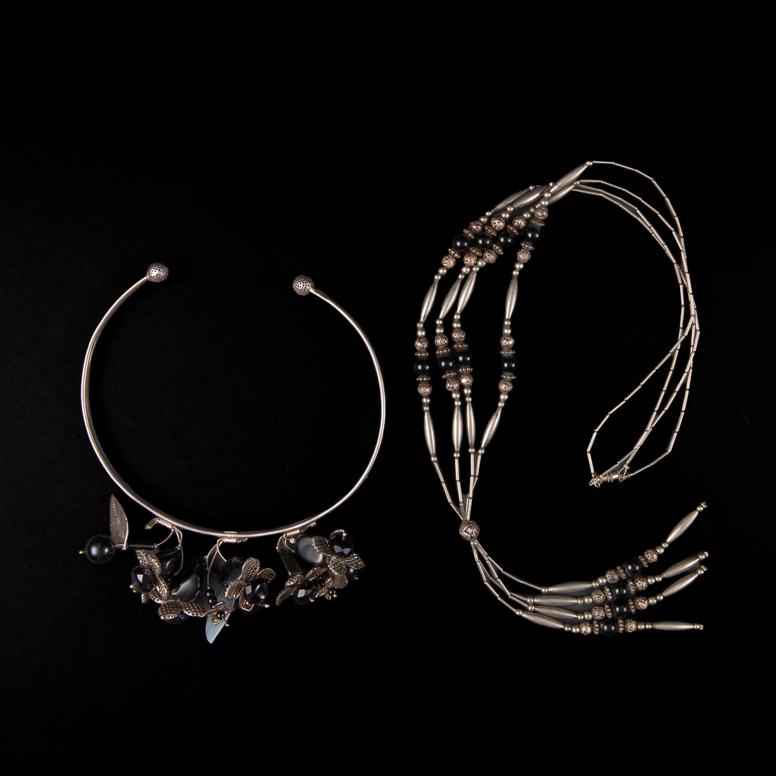 Two Mexican silver necklaces: A four-strand silver tube-bead necklace with onyx beads. A silver choker with silver and onyx flowers marked “Antigua 925 Mex SV-62.” Length of necklace 18 ½, circ. of choker 12 with 2