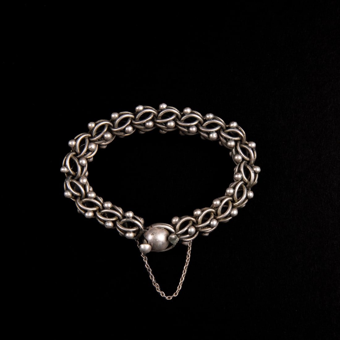 A Mexican silver bracelet: The Taxco silver chain and ball link bracelet, with small link chain attached, marked “Taxco, Mexico, V.J.” Interior dia. closed 2 ¾ in. Gross weight 79 grams.