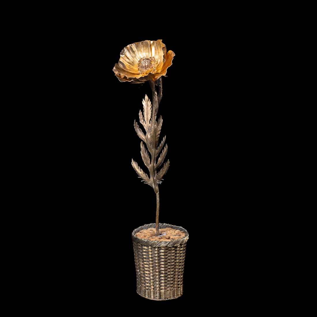 A Janna Thomas De Valarde silver poppy: Standing in a woven basket filled with caulk, the poppy with multiple leaves below the large flower, overall gold vermeil surface, the stem marked “Janna Sterling Mexico 538c,” the pot marked