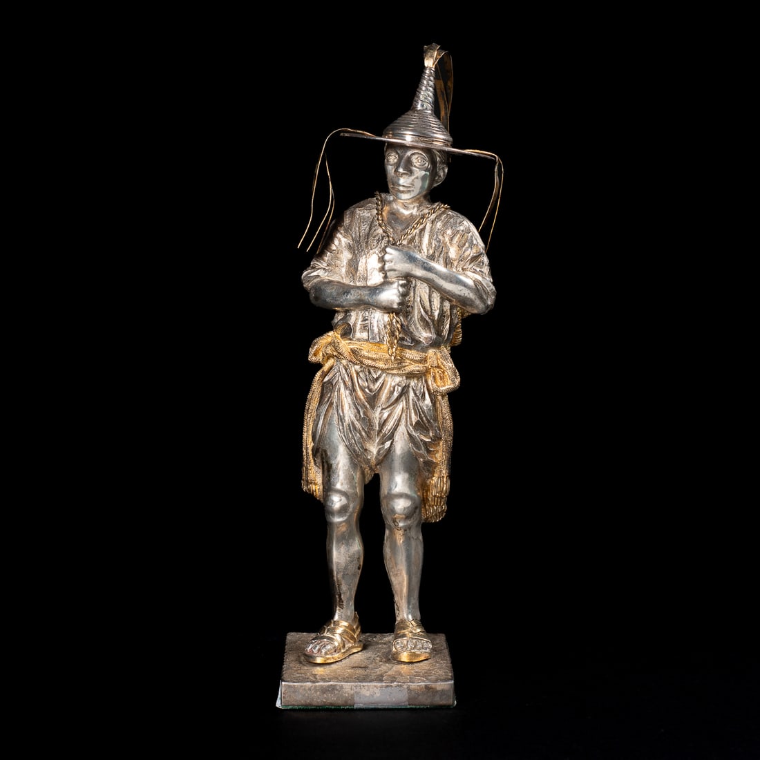 A Tane silver standing figure: The figure with removable hat with dangles at base and top, stands on square base, the figure detailed in full dress carrying detailed pack, modeled hands, feet, and facial features, all with shiny