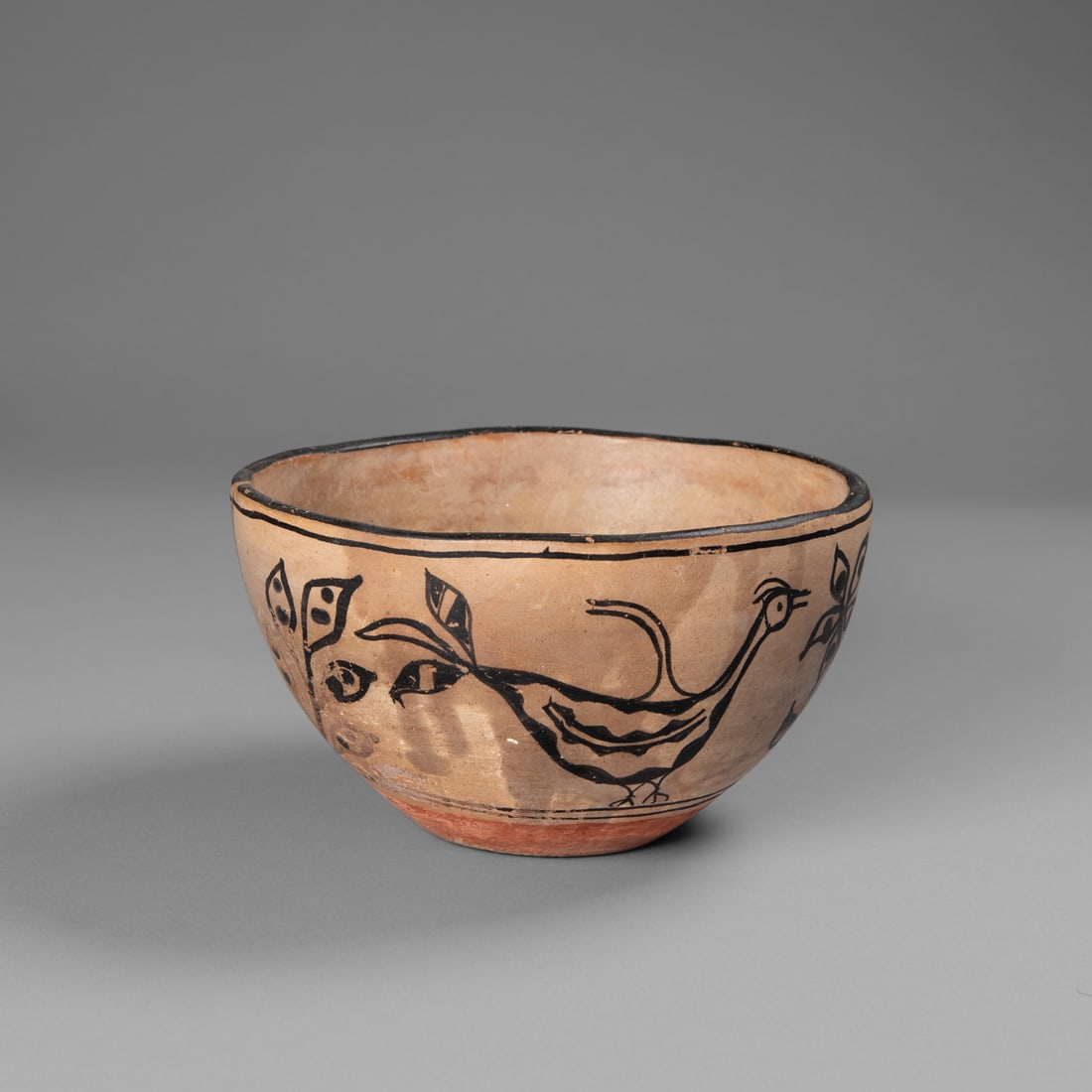 A San Ildefonso bowl: Early 20th century, the black rim with black band below, decorated with bird and floral motifs, paint loss. Ht. 4 ¾, wd.7 ¾ in.Provenance: The Tom Joyce Collection, Santa Fe, NM.