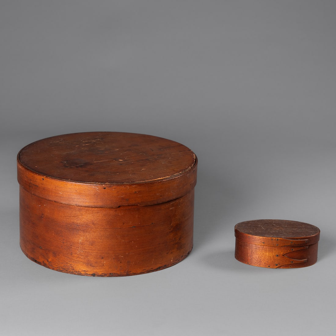 A Shaker bentwood box: 19th century, the small bentwood box with lid, with old paper label on the bottom, and signed on the inside of the lid, "Safford," together with a large bentwood cheese box. Ht. 1 7/8, lg. 4 1/2, wd. 