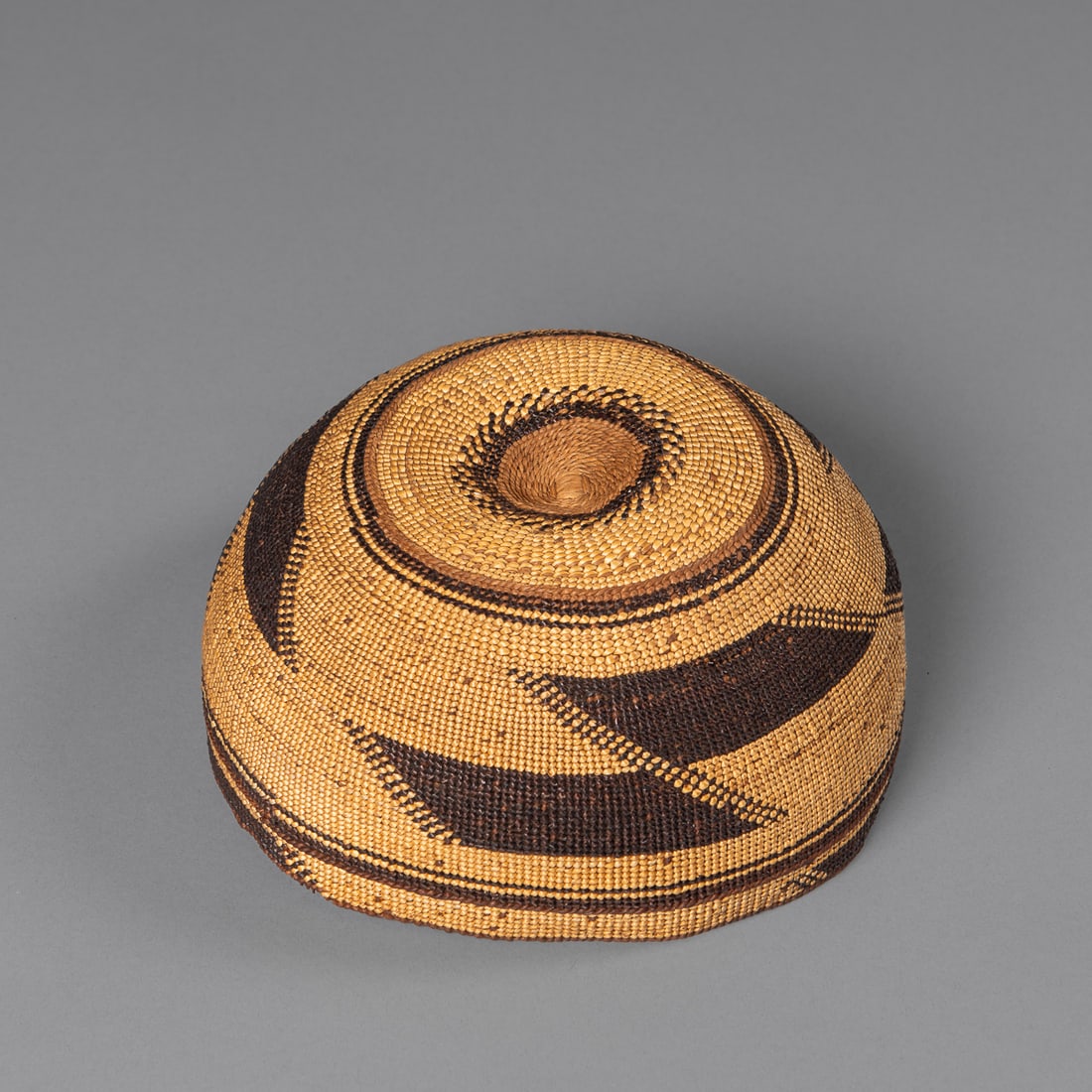 A Northwest California polychrome basketry hat: Hupa, early 20th century, decorated with traditional geometric designs. Ht. 3 1/2, wd. 7 in.