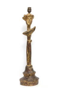 Syrie MAUGHAM (1879-1955) D’après le modèle d’Alberto Giacometti Pied de lampe à tête: Syrie MAUGHAM (1879-1955) D’après le modèle d’Alberto Giacometti Pied de lampe à tête de femme Plâtre à patine mordorée Marqué en dessous : « Made in England f