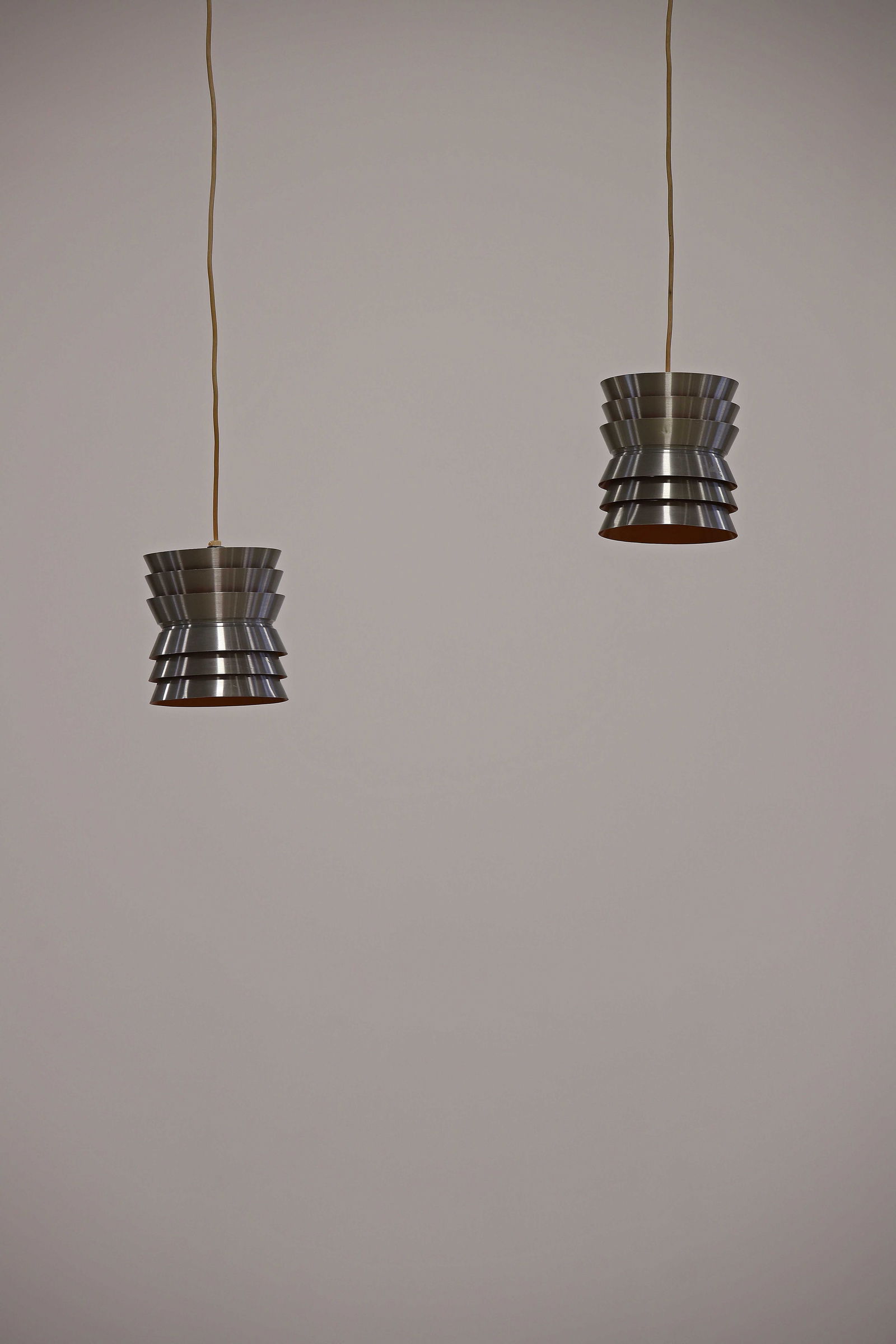 Carl THORE (XX) Suite de deux suspensions, circa 1960, Ã corps composÃ© de: Carl THORE (XX) Suite de deux suspensions, circa 1960, Ã corps composÃ© de disques incurvÃ©s de dimensions variables en acier chromÃ© et laquÃ© orang