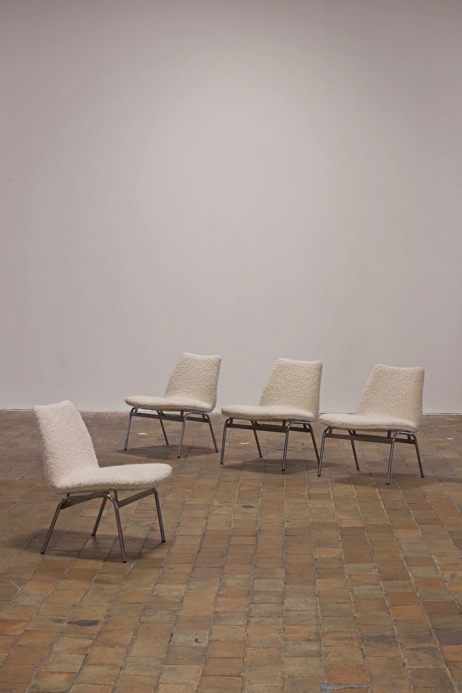 TRAVAIL FRANCAIS: TRAVAIL FRANCAIS (XX) Suite de quatre chaises, circa 1975, à assise et dossier recouverts d'un drap de laine blanc, disposé sur un double piètement tubulaire en acier chromé joint par des entretoi