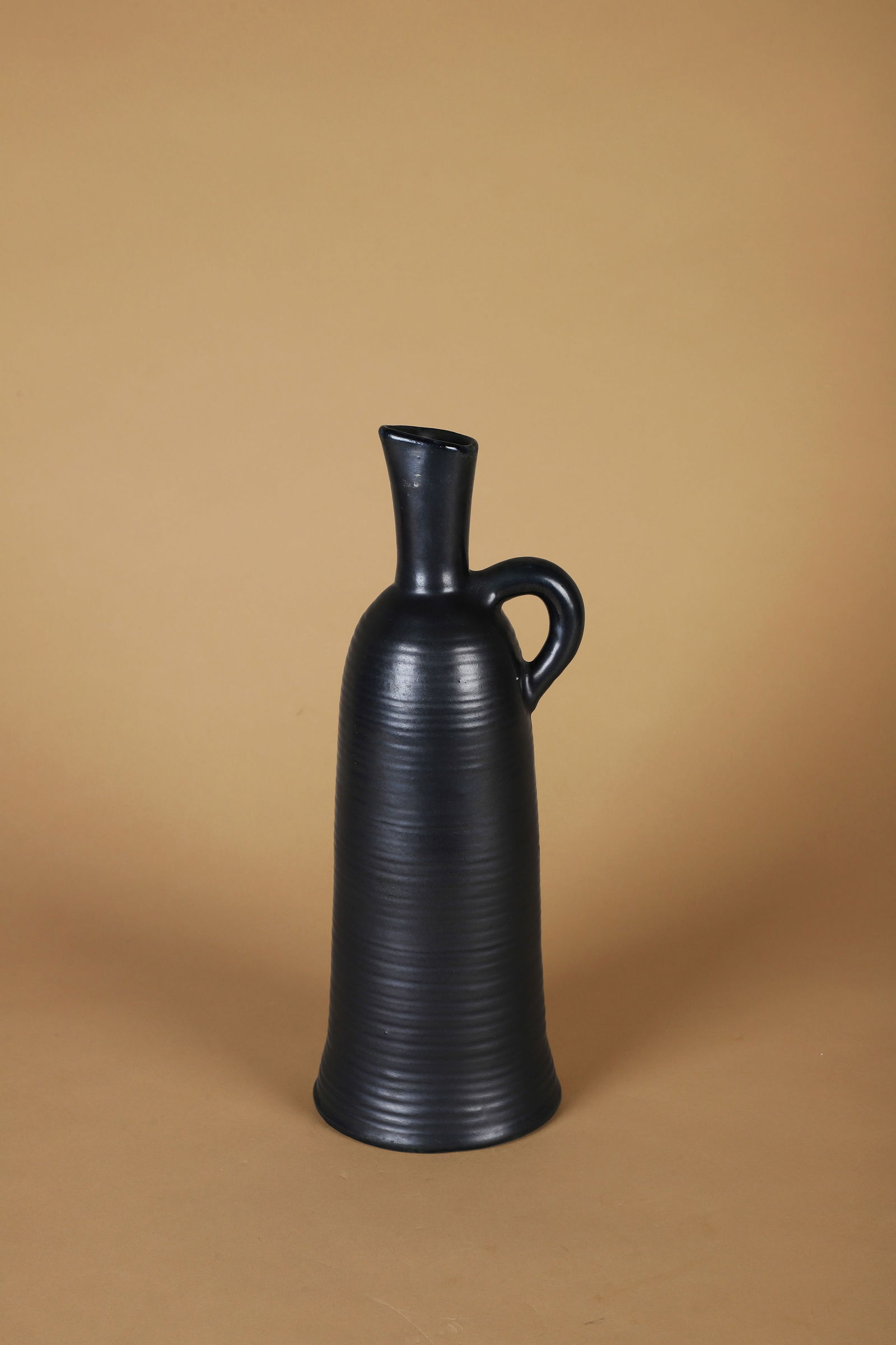 ACCOLAY (Actif de 1945 à 1983): Pichet à anse anneau, circa 1950 Épreuve en céramique émaillée noir Signé Accolay sur l’envers H. : 31.8 cm (Défauts d’émaillage)