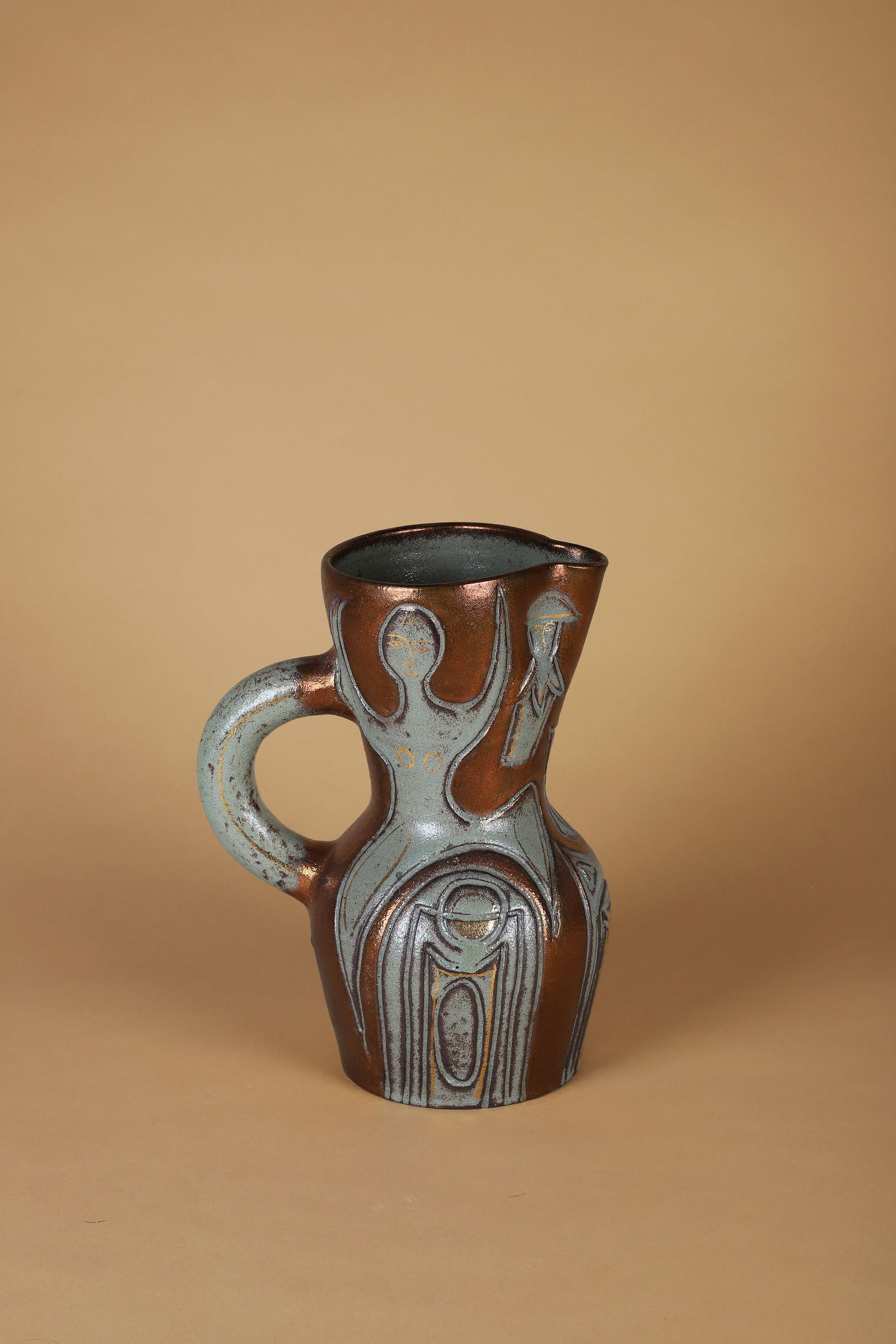 ACCOLAY (Actif de 1945 à 1983): Pichet à anse, circa 1960 Épreuve en céramique émaillée dans les tons vert, bronze et or à décor tournant de personnages Signé Accolay sous la base H. : 30.5 cm