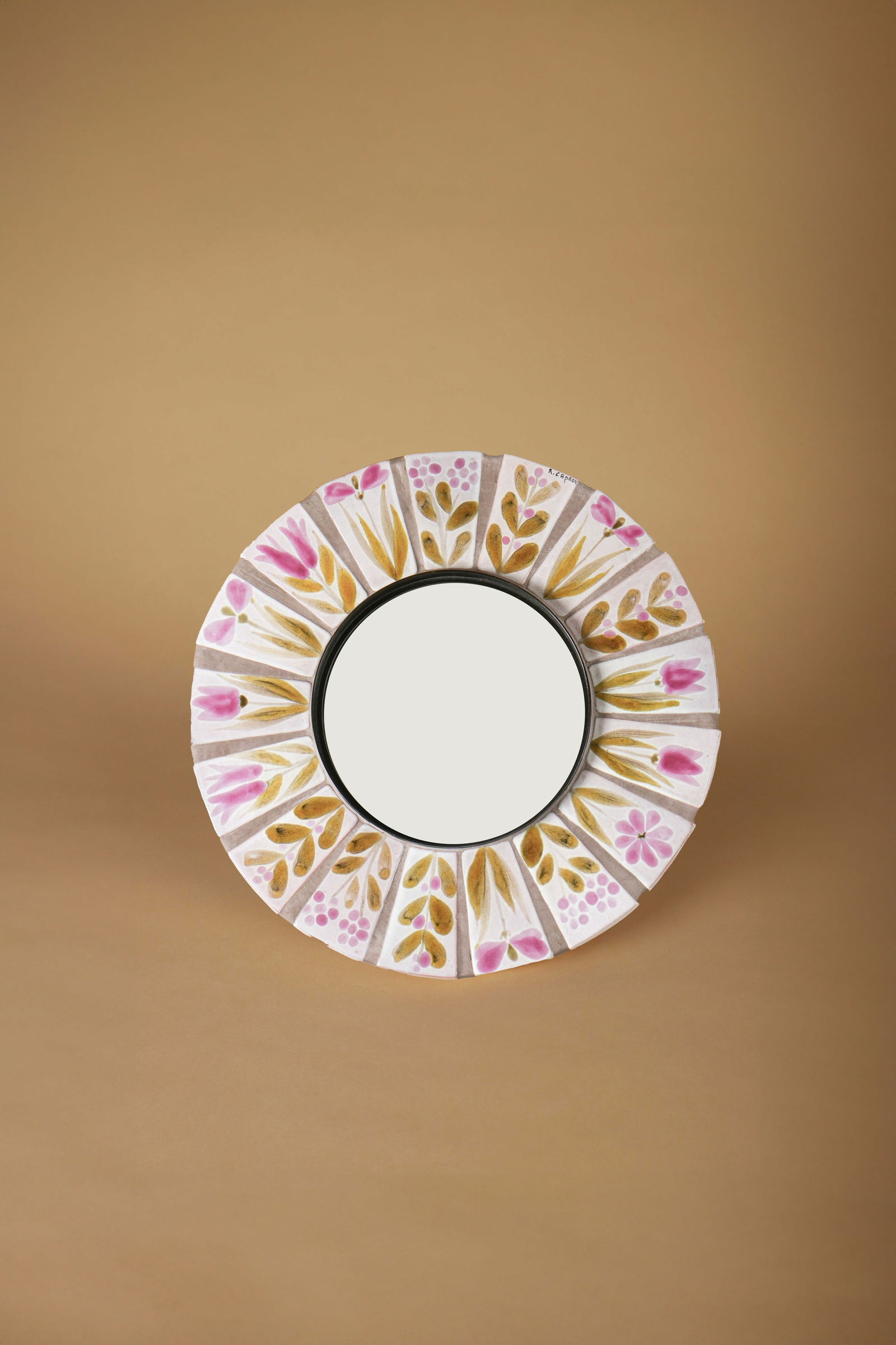 Roger CAPRON (1922-2006): Miroir mural circulaire, circa 1960Épreuve en faïence émaillée polychrome à décor floralSigné Capron sur le côtéH. : 26.5 cm. - D. : 39 cm.