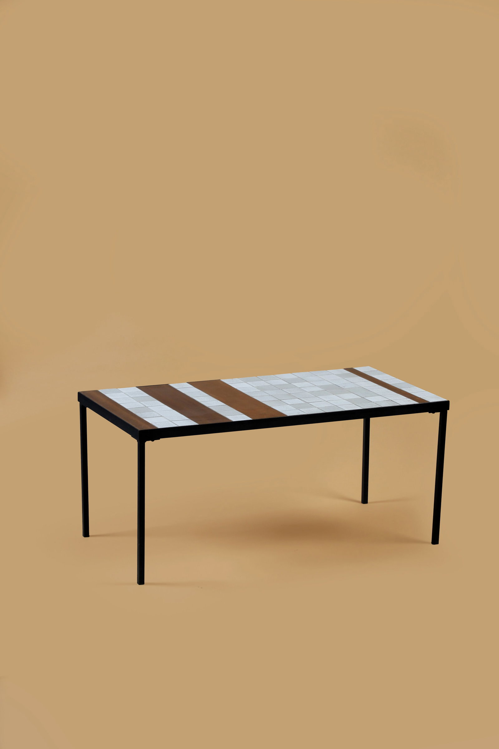 Roger CAPRON (1922-2006): Table basse de la série T, circa 1962, à plateaurectangulaire orné de carreaux en céramique griset blanc et de trois lames en teck disposé sur unestructure en métal laqu&