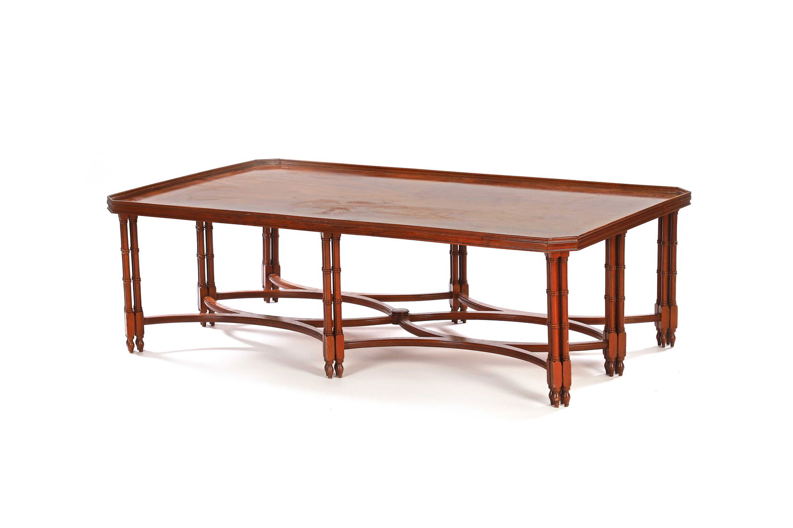 Madeleine CASTAING (1894-1992) d’après: Table basse, en acajou à plateau rectangulaire à pans coupés, reposant sur huit pieds en forme de colonnettes multiples imitant le bambou réunis par une entretoise sinueuse.H. : 47