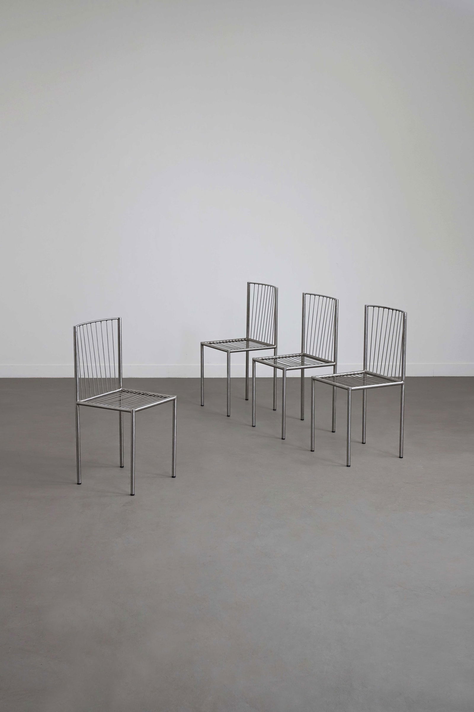 Philolaos TLOUPAS (1923-2010): Suite de quatre chaises, circa 1960, à structure en acier tubulaire formant un dossier en arc de cercle et quatre pieds d’angles, l’assise et le dossier composés de barreaux fix&