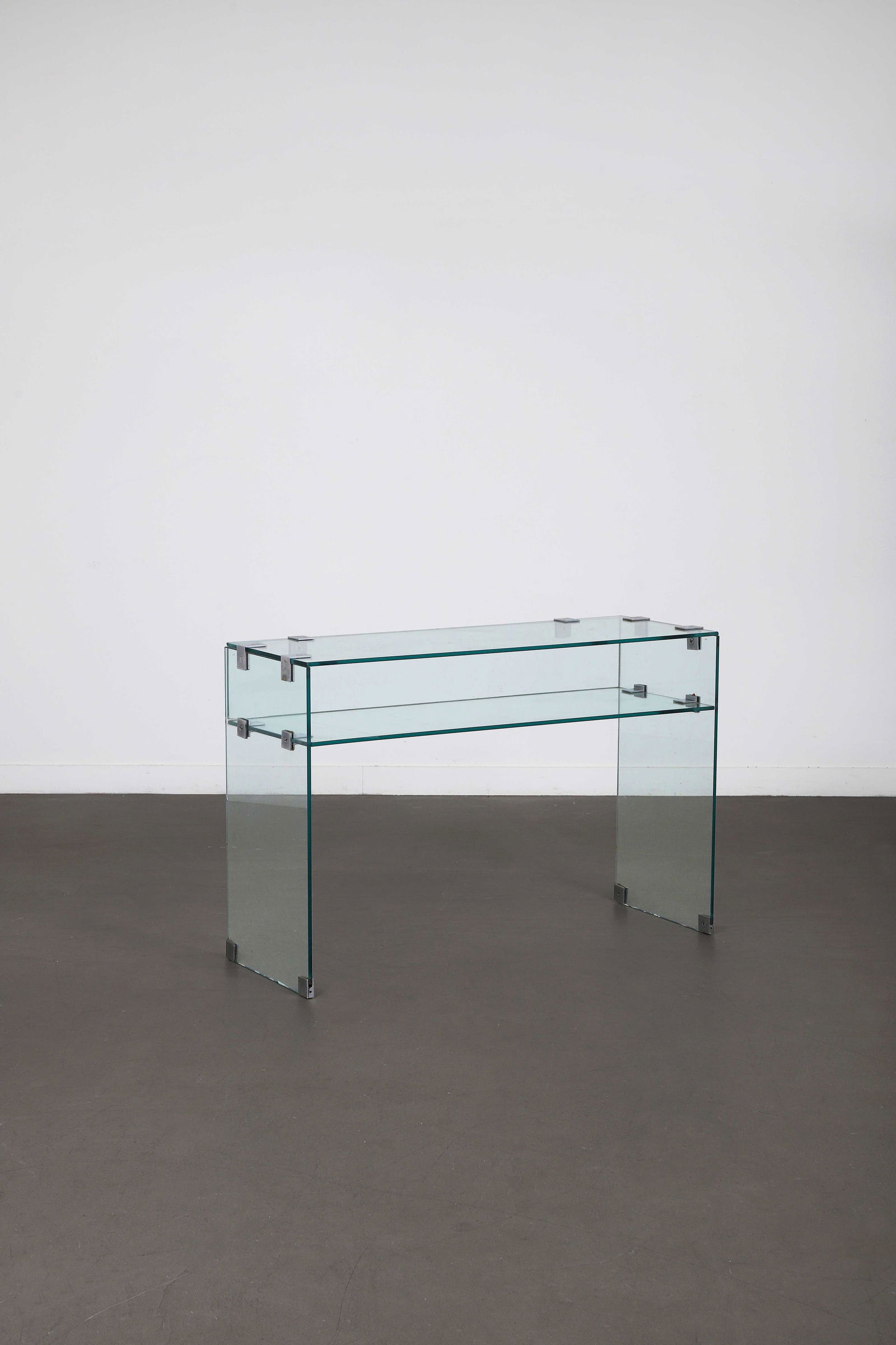 Jacques ADNET (1901-1984): attribué à Console, circa 1950, à double plateaux en verre,assemblées par des vis et équerres en acierà deux panneaux latéraux formant jambages.H. : 81 cm. - L. : 12