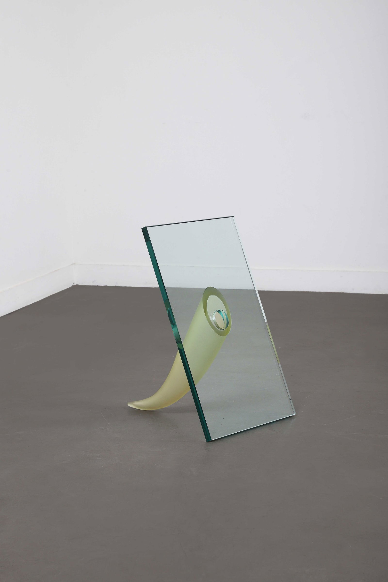 Philippe STARCK (1949): Vase modèle Une étrangeté sous un mur, 1990, représentant une corne d’abondance en verre satiné jaune fixé sur une épaisse dalle de cristal.Signature manuscrit