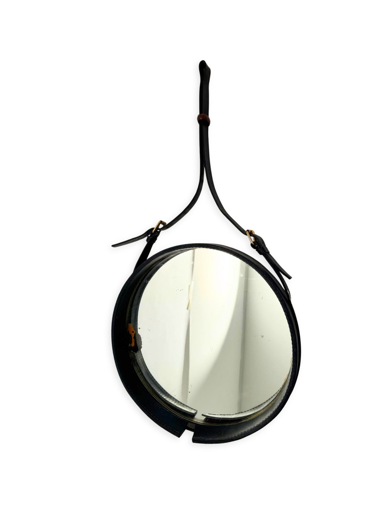 Jacques ADNET (1900 - 1984) Attribué à: Miroir mural circulaire entièrement gainé de cuir noir aménagé de sa lanière d'attache à hauteur réglable et ses boucles en laiton.H. : 64 cm D. 31 cm.(Usures,
