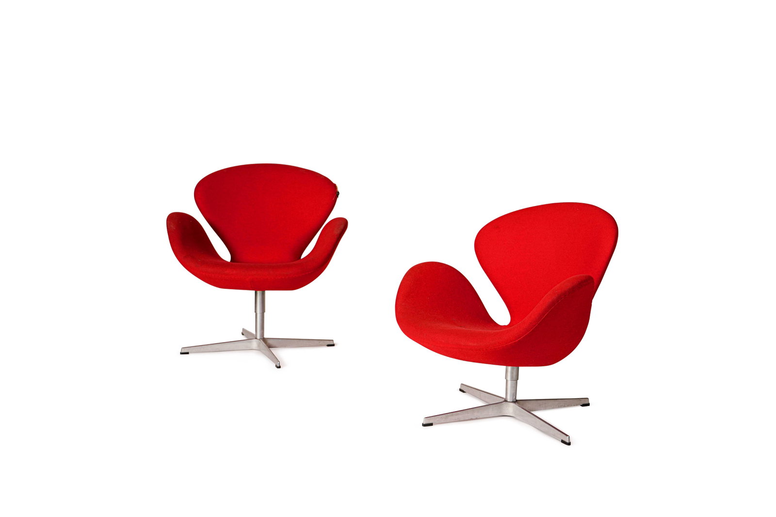 Arne JACOBSEN (1902-1971): Suite de deux fauteuils modèle Swan, à assise et dossier garnis de mousse et recouverts de drap de laine rouge, disposés sur un piètement cruciforme en fonte