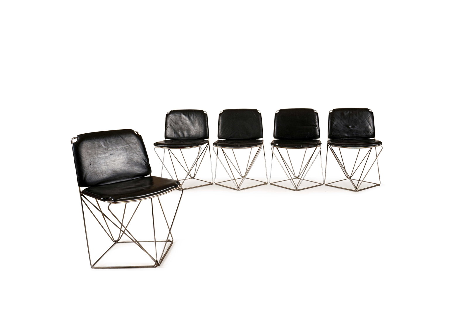 TRAVAIL FRANÇAIS (XX): Suite de douze chaises à assise et dossier en cuir noir reposant sur une structure tubulaire formant un piètement stylisé.H. : 79 cm. - L. 50 cm. - P. : 52.cm.(Usures, rayures)