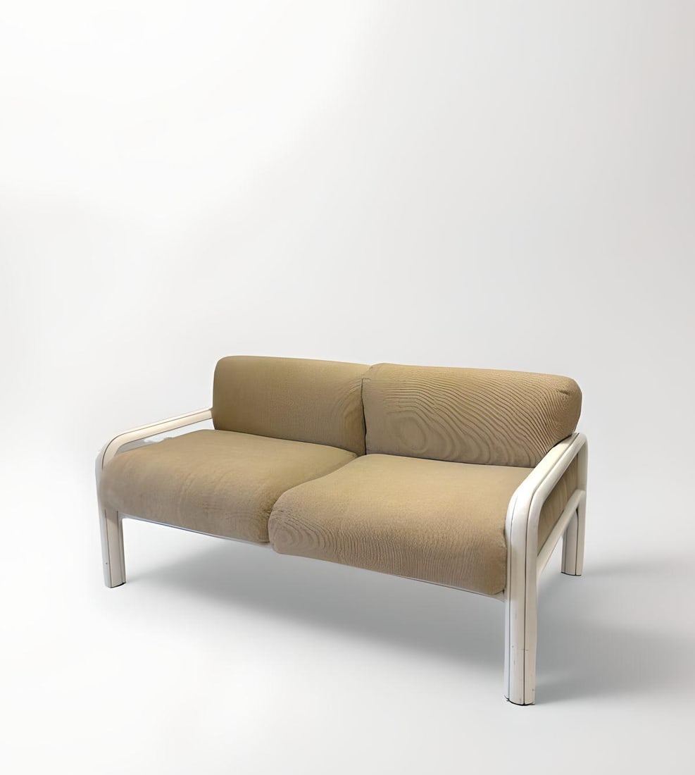 Gaetana AULENTI DIT GAE (1927-2012) : Canapé deux places, circa 1980, à coussins d’assise et de dossier en toile de coton sable disposés sur une structure en acier plié gainé époxy de couleur blanc