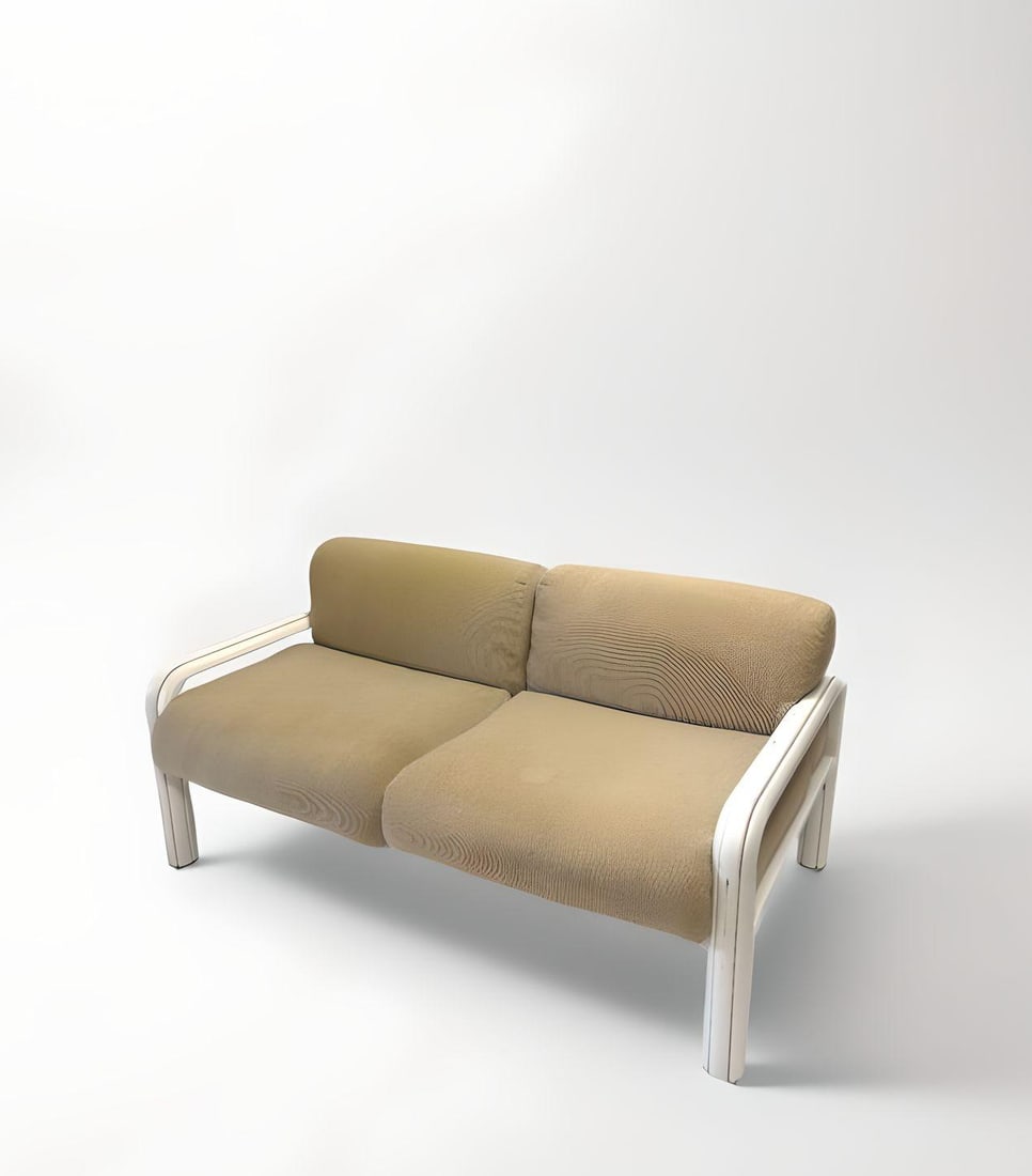 Gaetana AULENTI DIT GAE (1927-2012) : Canapé deux places, circa 1980, à coussins d’assise et de dossier en toile de coton sable disposés sur une structure en acier plié gainé époxy de couleur blanc form