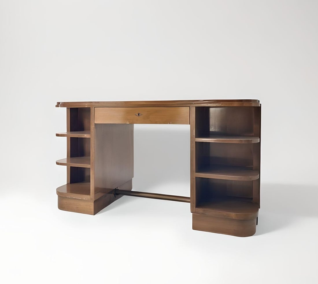HUGUES CHEVALIER (XX°): Bureau en bois teinté, circa 1980, à plateau rectangulaire aux bords arrondis aménagé d’un sous-main en cuir taupe reposant sur structure formant des niches traversantes