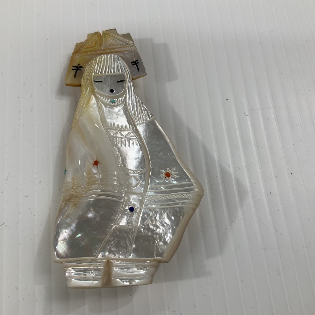 Corn Maiden Sandra Quandelacy Zuni, New Mexico: Hand carved gold lip shell with inlaid coral, turquoise, lapis lazuli and sugilite. The corn maiden is a metaphysical part of the Zuni tradition. She brought corn and other good things to the Zuni peo