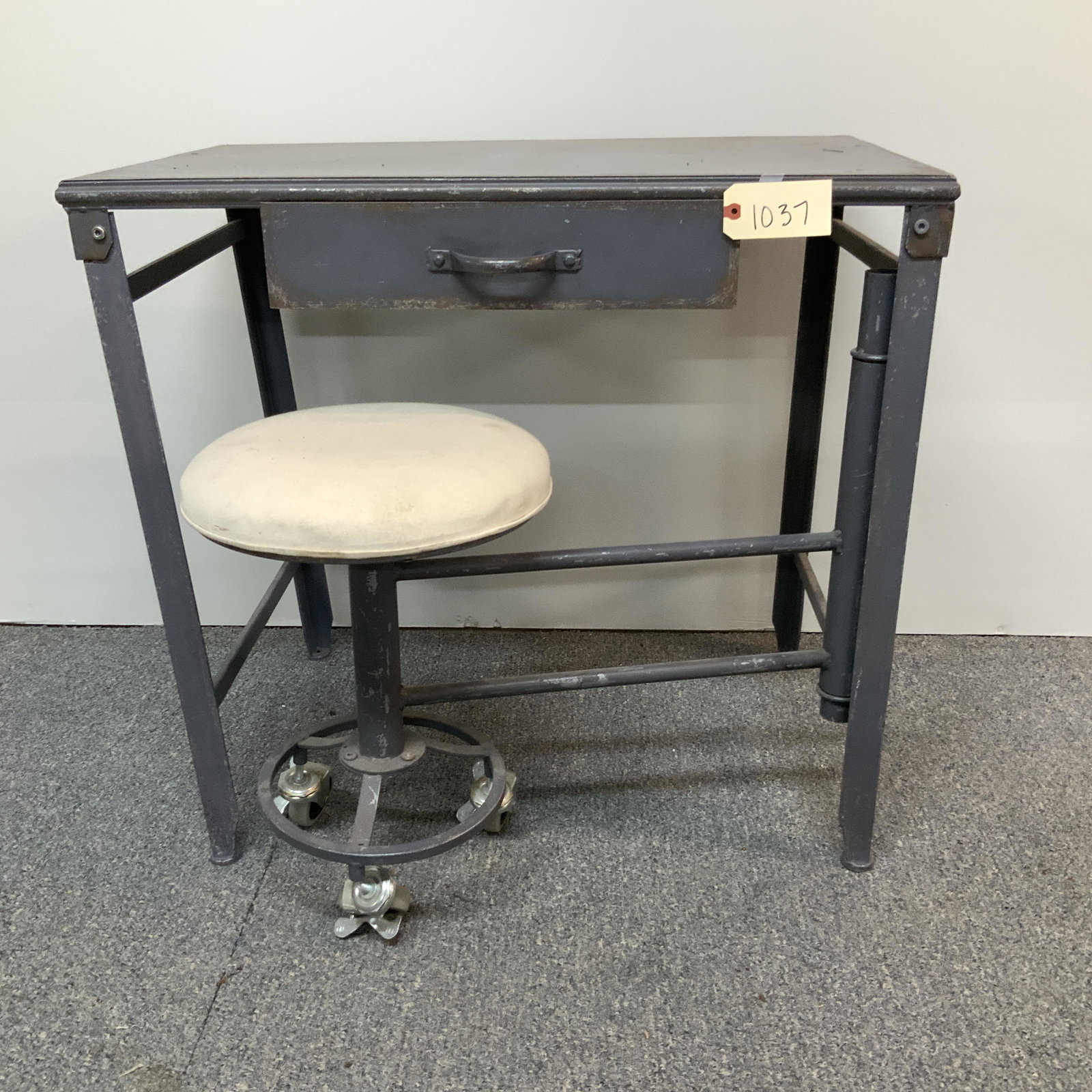 Metal Industrial desk with swing seat: Gray metal industrial desk/workstation with drawer and swing out stool. Measures 32 x 29 x 20