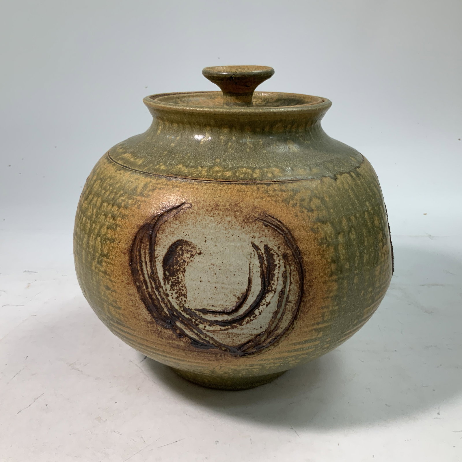 Artisan-made Glazed Pot: A covered artisan-made glazed pot with lid and pressed/incised decoration and earth-tone glaze. Approx 9" in diameter and 9 1/2" high.