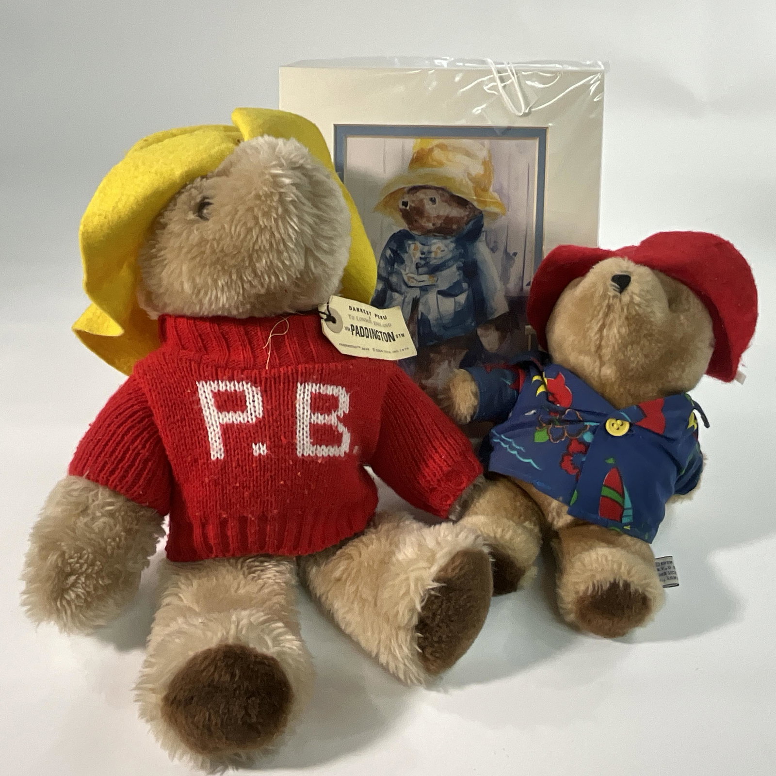 Pair of Paddington Bears: A 12" wearing a red sweater, and an 8 1/2" in a Hawaiian shirt. Also includes a framed 8" X 10" Paddington print.