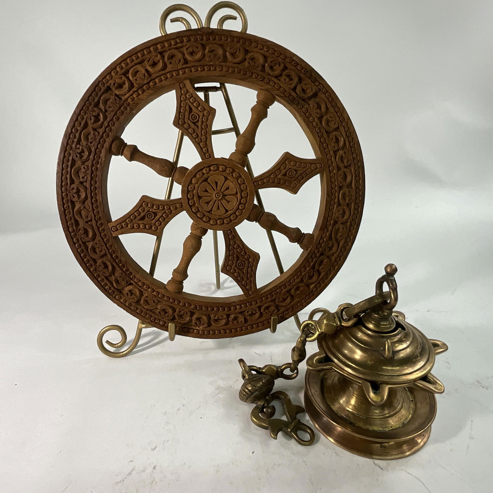 Indian Carved Wheel and Hanging Oil Lamp: Indian teakwood carved wheel (12" diameter) and a heavy brass Diya hanging oil lamp, acquired in India, 1957. Lamp is approx. 4 1/4" in diameter and 6" tall (approx. 16" tall with hanging chain).