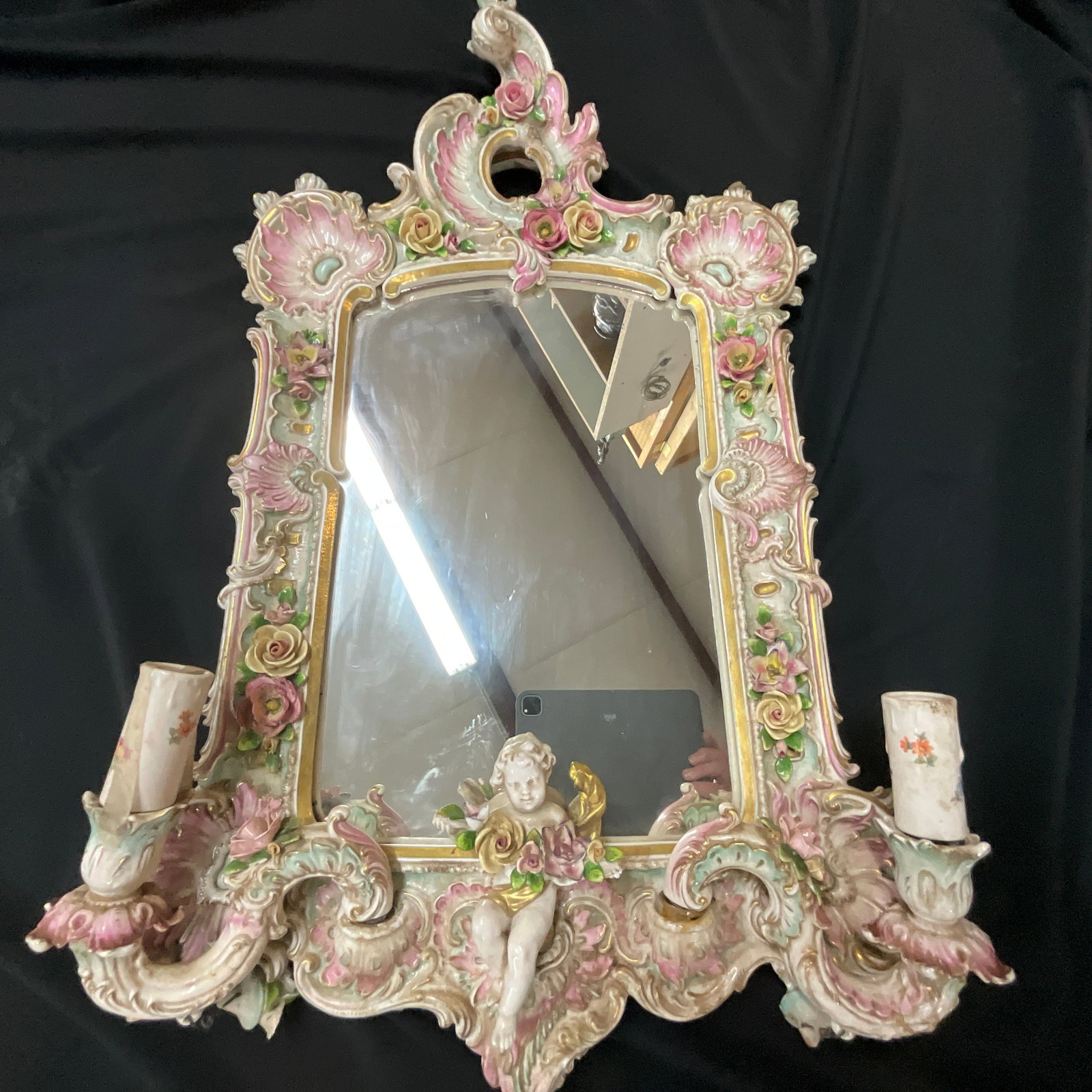 Capodimonte Mirror: Capodimonte Mirror with two removable candle arms and cherub figure. Approx. 20"X30". One candle arm has been broken and repaired.