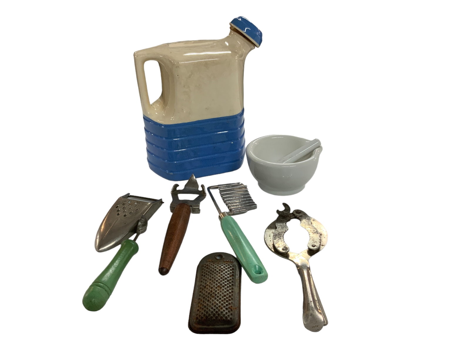 Kitchen Assortment, Lot of 8: Kitchen assortment including cheese slicer, jar opener, bottle/can opener, microplane, mortar/pestle, potter water jug. Milk jug measures approx. 8 3/4" tall, 4 1/2" wide, 7 1/4" deep.