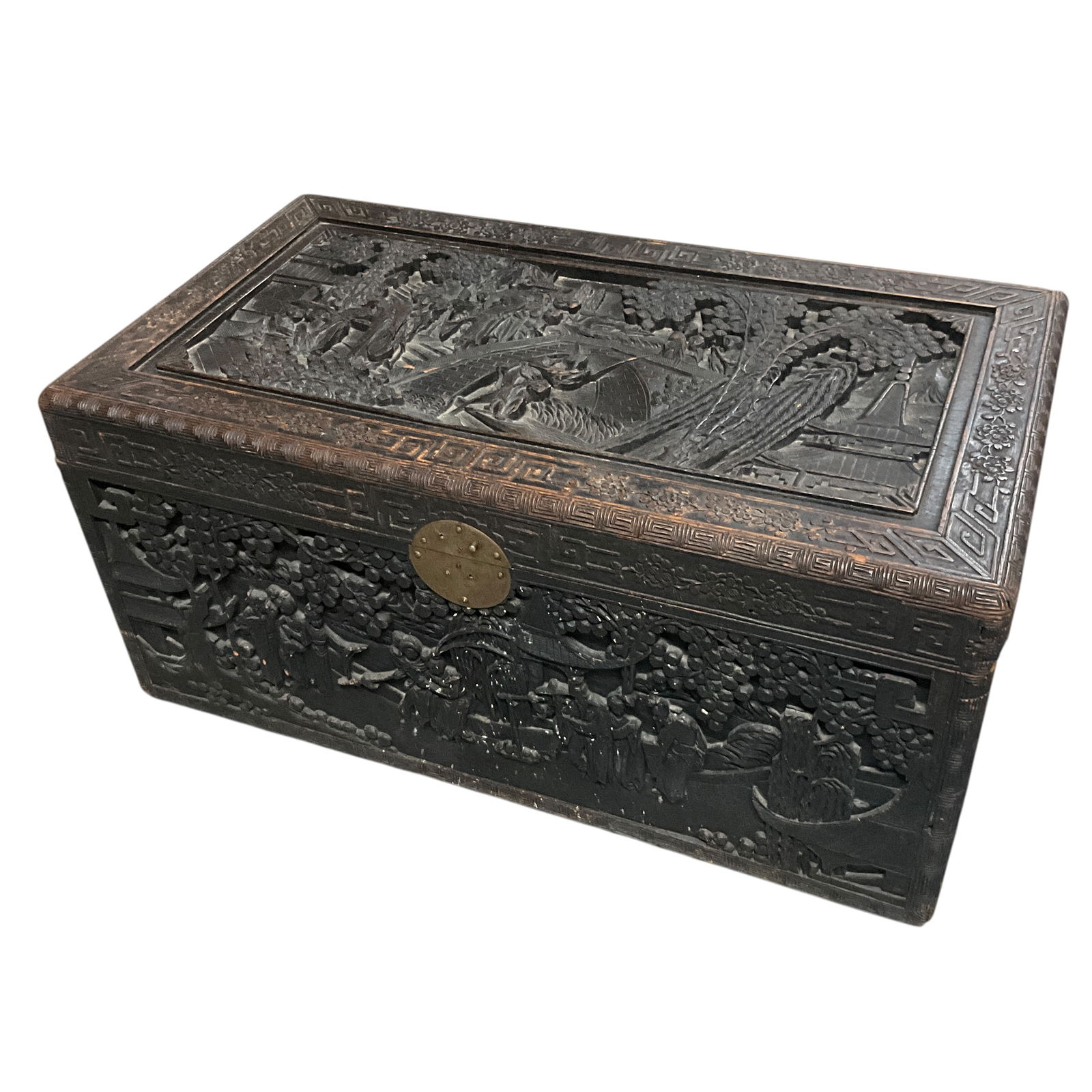 Heavily Carved Asian Trunk: Heavily Carved Asian Trunk. Carved on all four sides and lid with deep and detailed carvings. Lid features a bridge over a river with a boatman, buildings, people, and trees and bamboo stands. There i