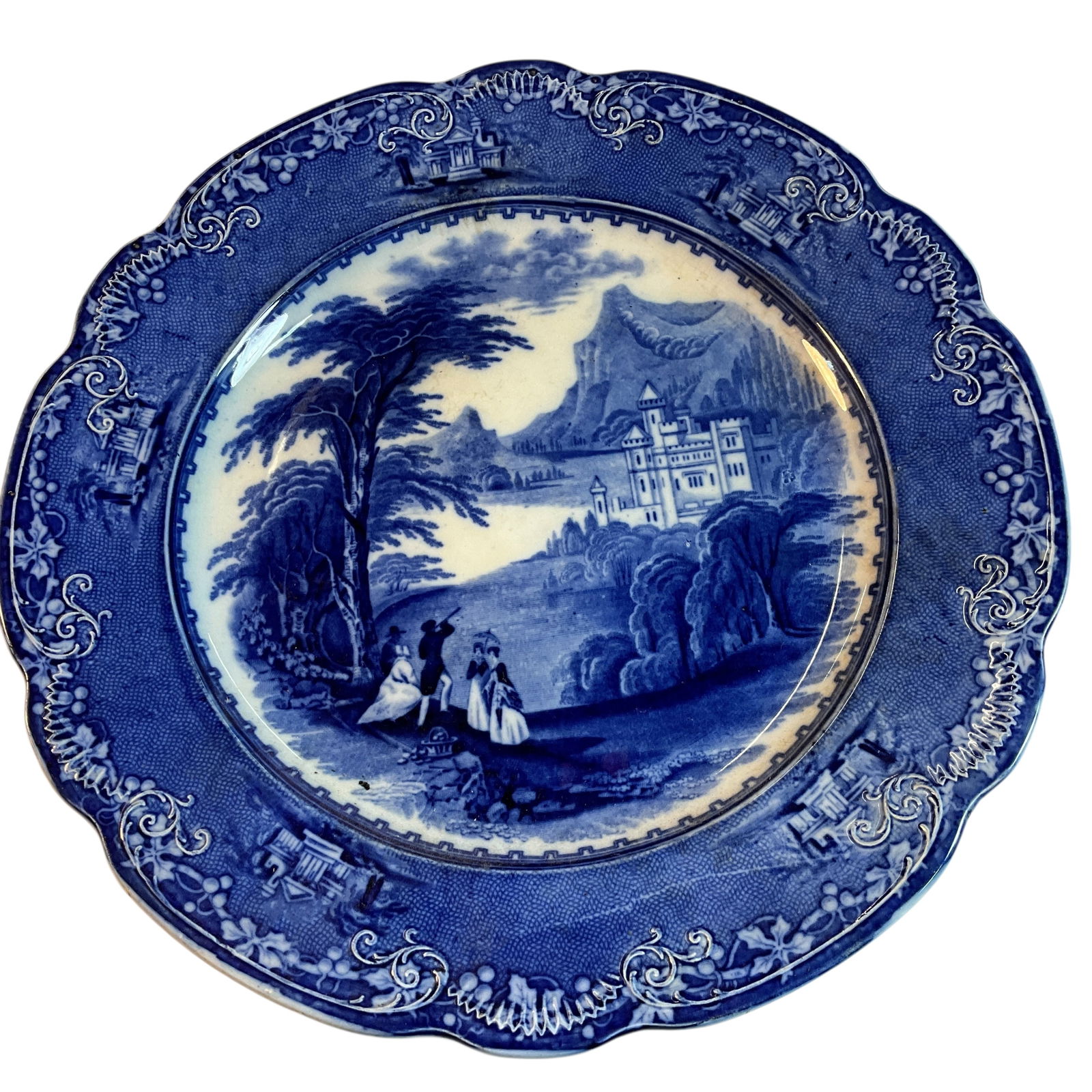 Great Flow Blue Charger: Great Flow Blue Charger- Scene of Mountains and a castle on a lake, with a picnicking group in the foreground. Raised decoration around the edge. Grapevine cartouche on back, marked "Jenny Lind CM U.