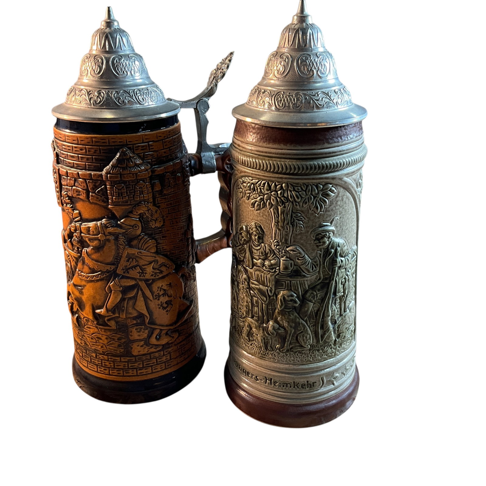 Two German Figural Steins: Two German Figural Steins. One has a scene of a mounted knight in full armor, and one features a hunter enjoying a drink after a hunt. Both have pewter lids, and both are about 11" high.