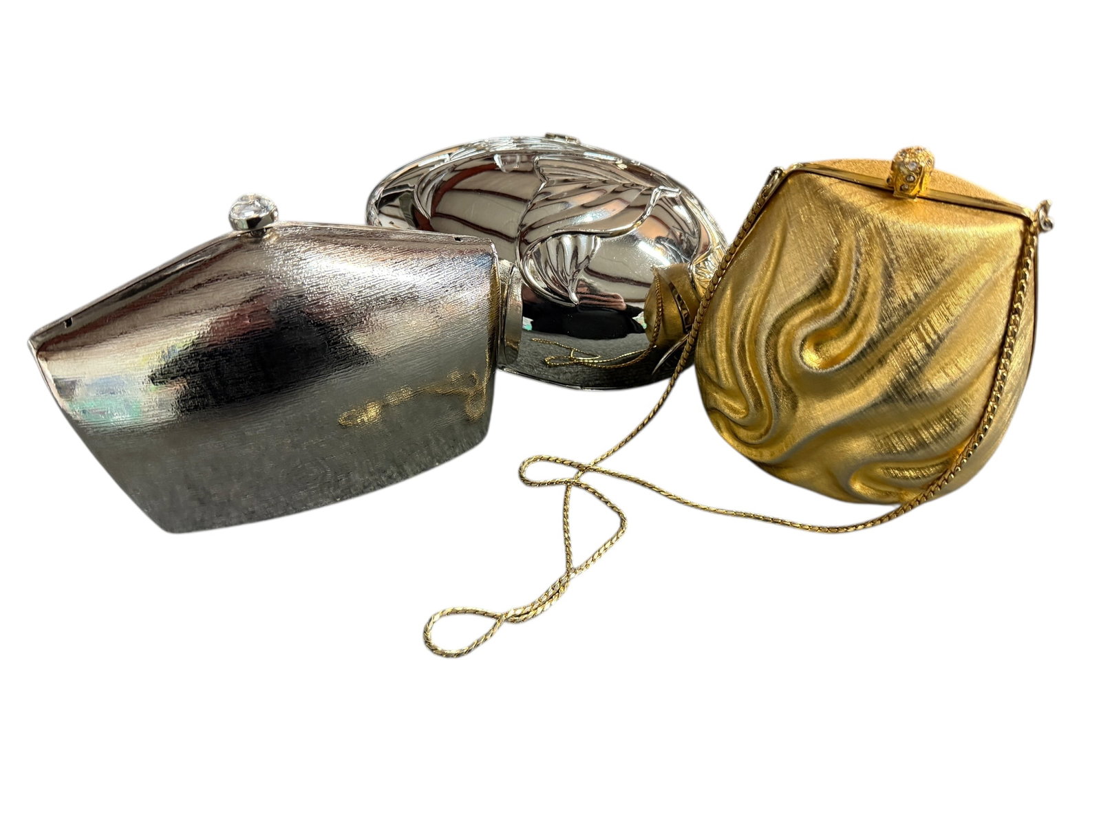 Vintage Hard Case Bags: The trio of evening clutches showcases a striking blend of metallic elegance and sculptural artistry. Gold "pouch" shaped bag is an Italian bag made for Walborg. The Silver "envelope" shaped bag is No