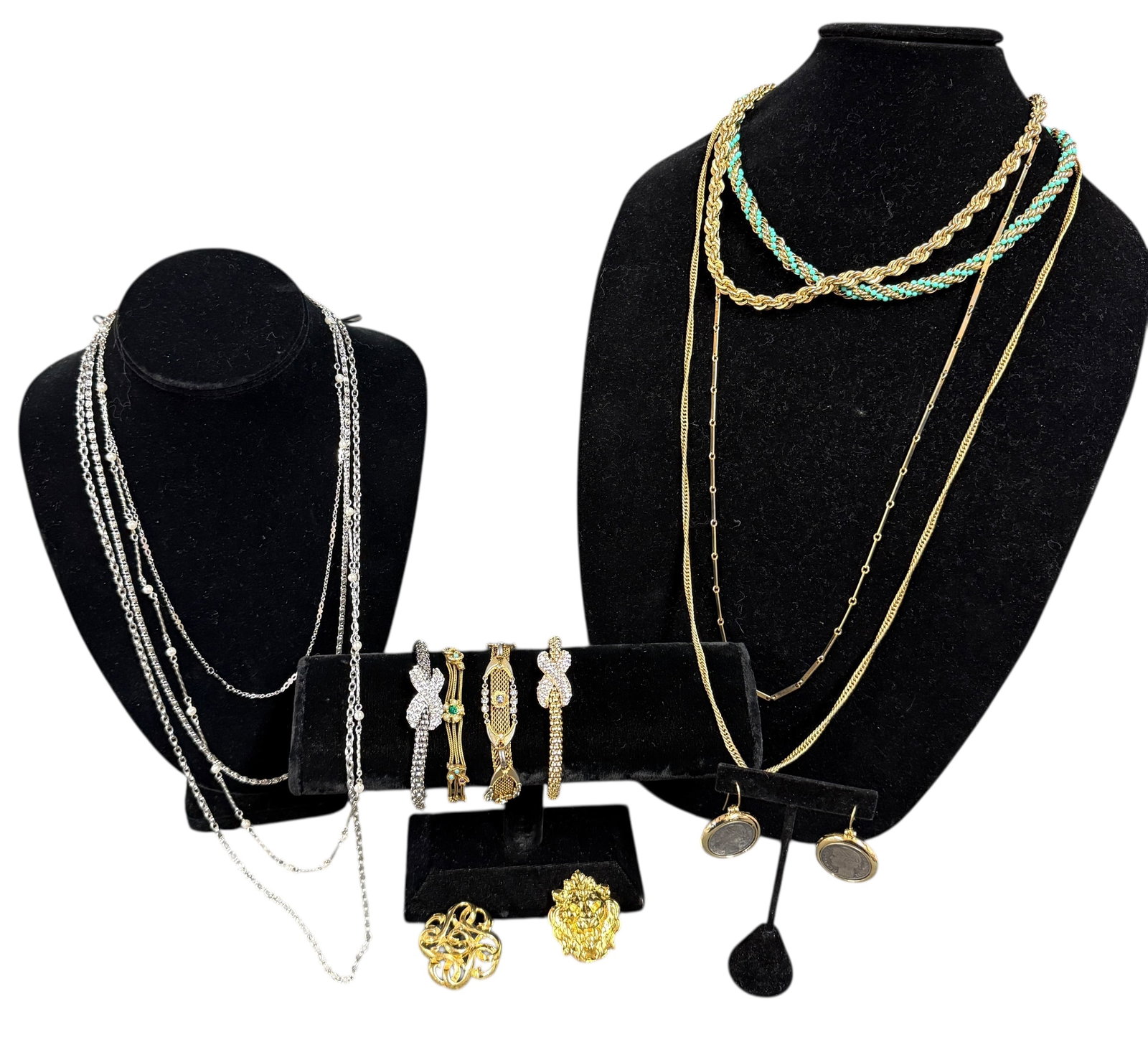 Vintage Collection of Costume Jewelry: This group of vintage jewelry features a striking mix of silver and gold pieces arranged with a sense of balance and elegance. On the left, several silver necklaces showcase varied chain styles and le