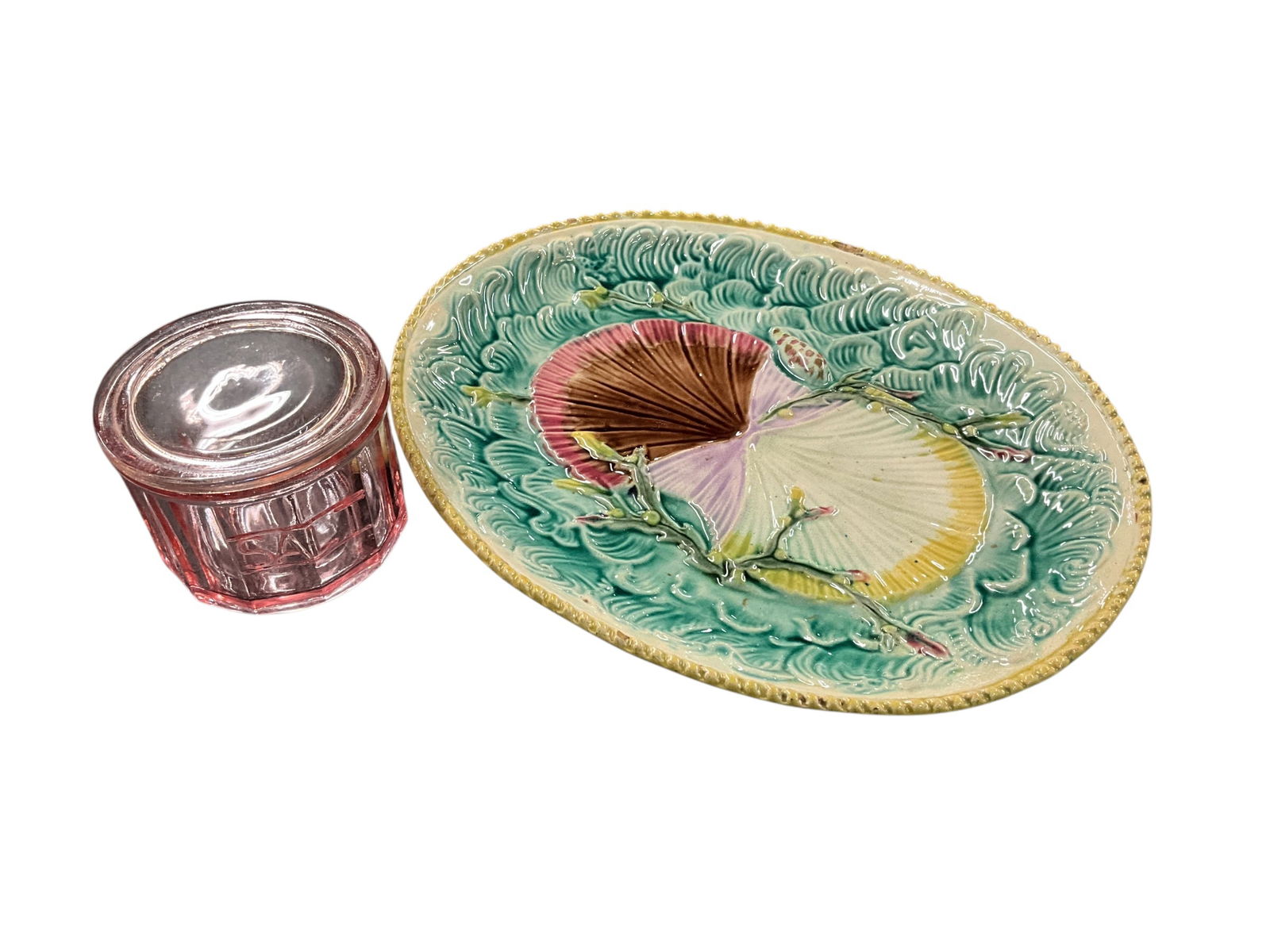 Majolica, Depression Glass: Majolica, Depression Glass. A Shells and Seaweed on Waves pattern oval platter, approx. 13.75" X 11.25." Platter has a number of rim chips. Also a pink depression glass covered salt container,