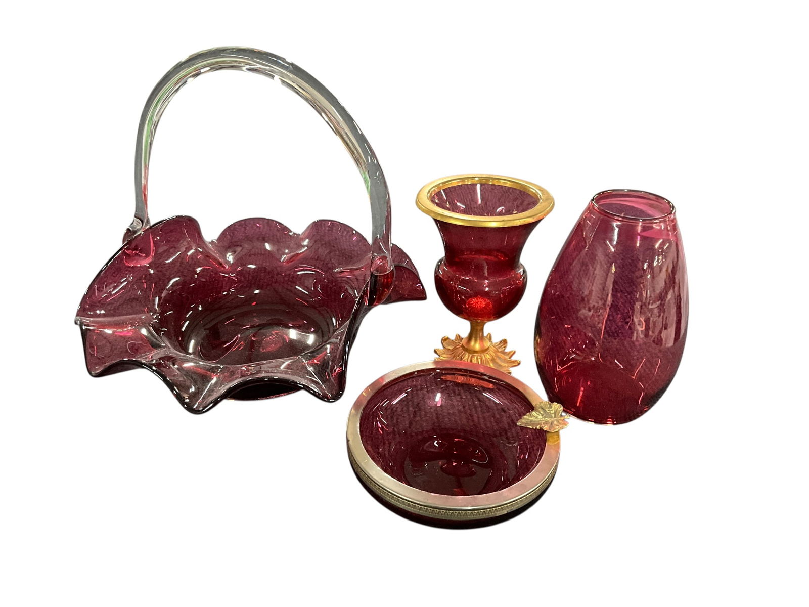 Cranberry Glass Lot: Cranberry Lot. A 9" high Fenton Blown Glass basket with ruffled rim and applied handle, a 5" cranberry vase with brass base and rim, a dresser dish with metal rim, and cone shaped vase.